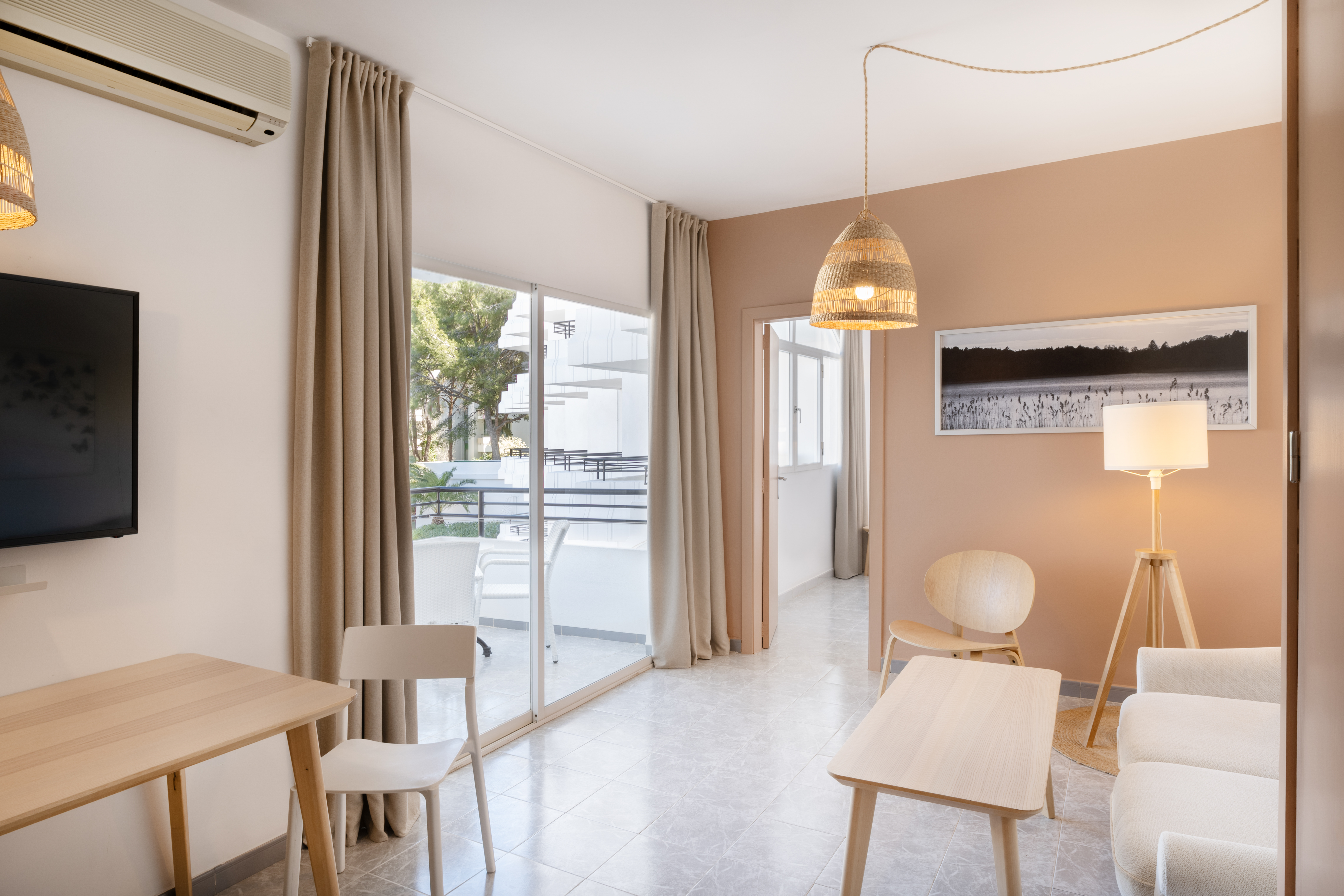 Modern apartment living room with light decor, wooden furniture, and balcony.