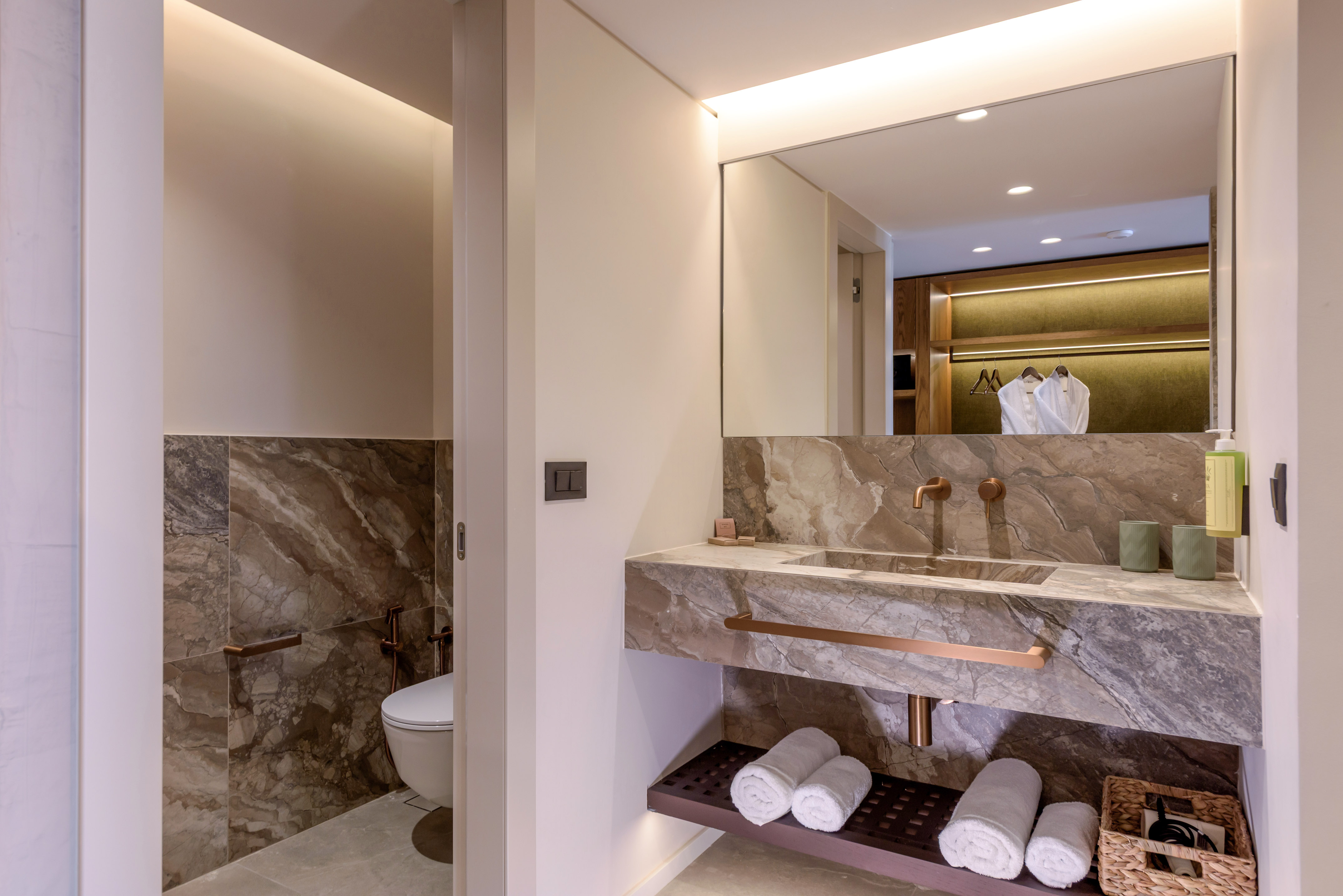 Modern luxury bathroom with marble vanity, copper fixtures, and fresh towels.