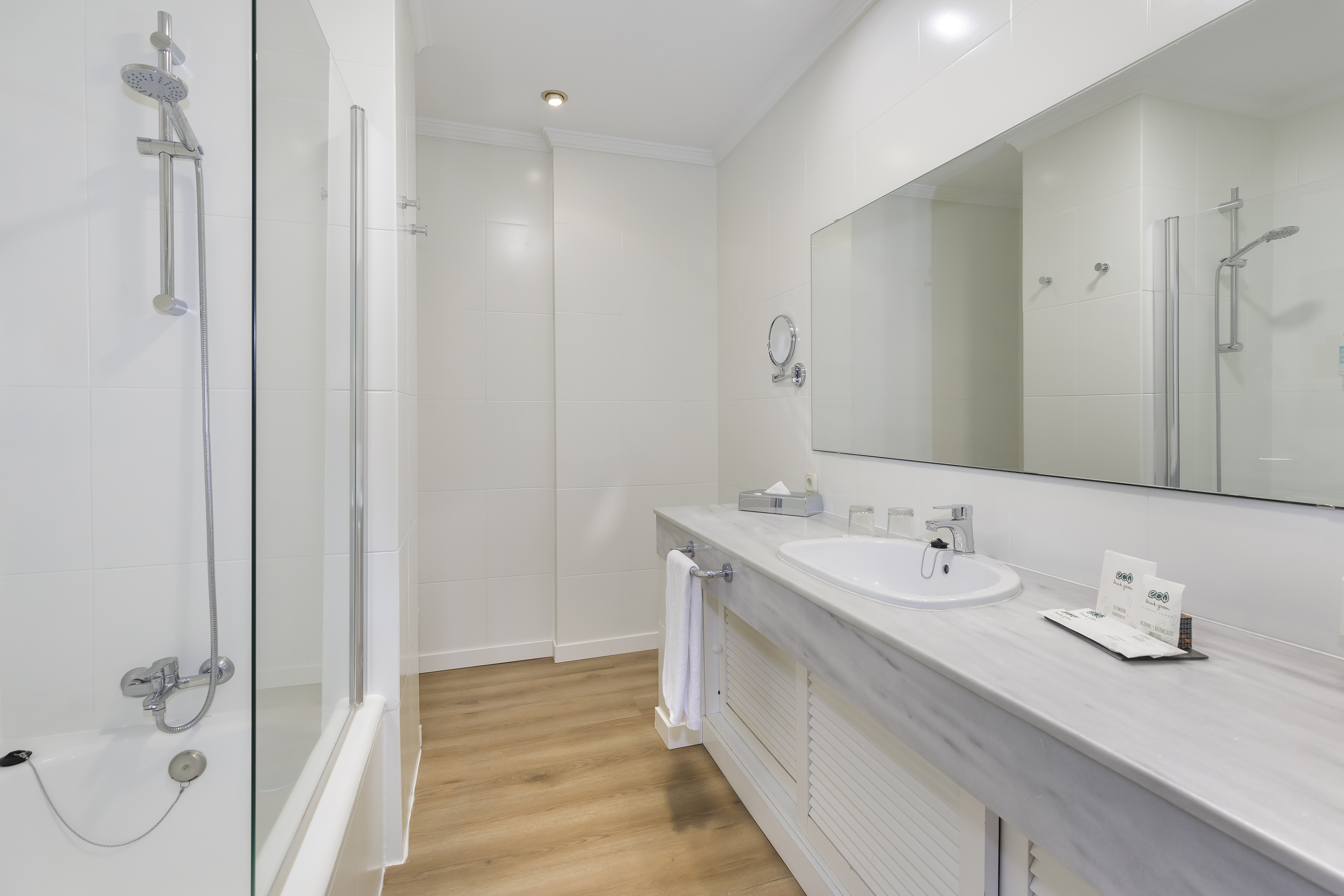 Bright, clean hotel bathroom with shower, bathtub, vanity, and mirror.
