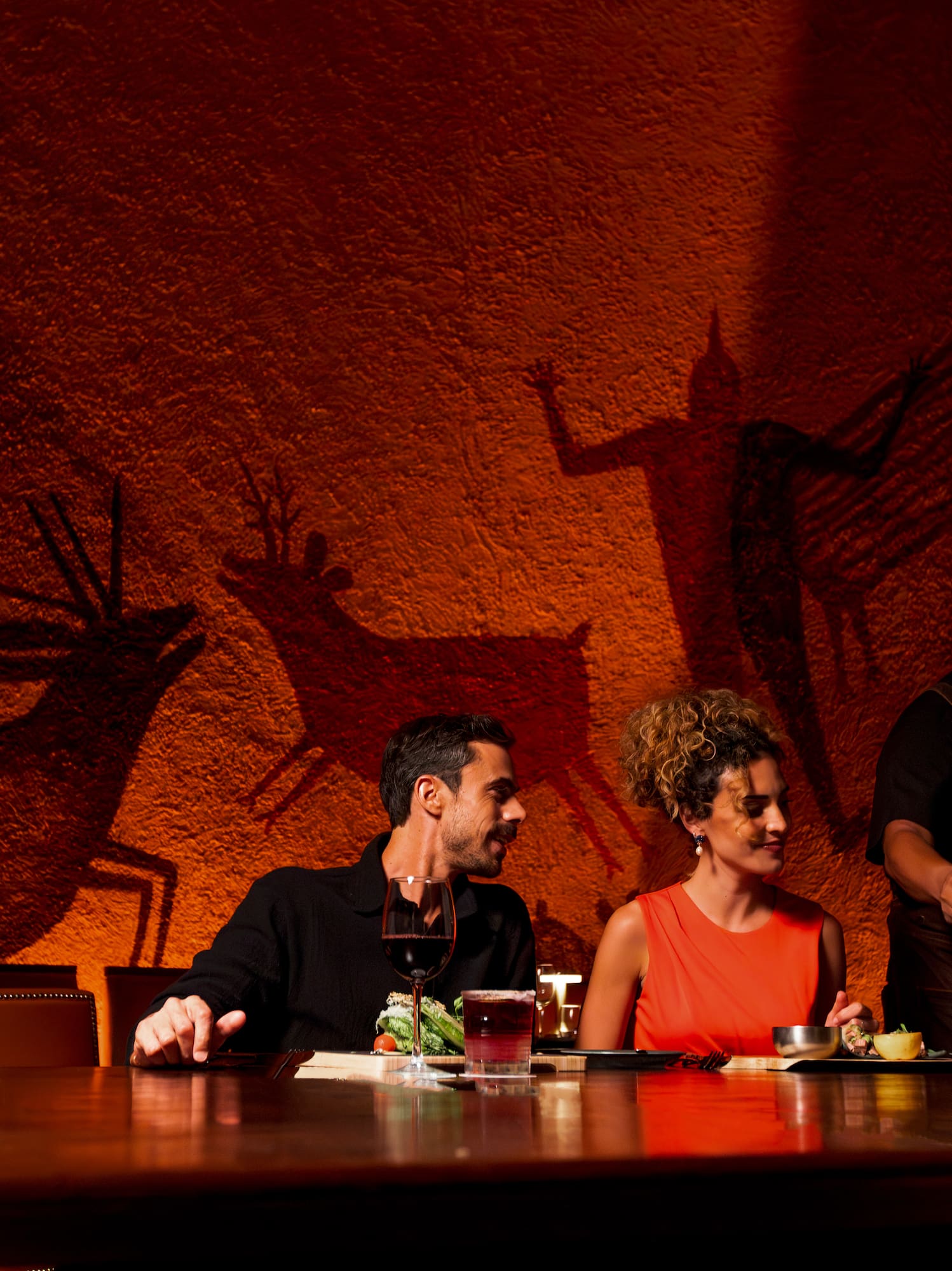 a group of people sitting at a table with a bottle of wine