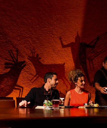 a group of people sitting at a table with a bottle of wine