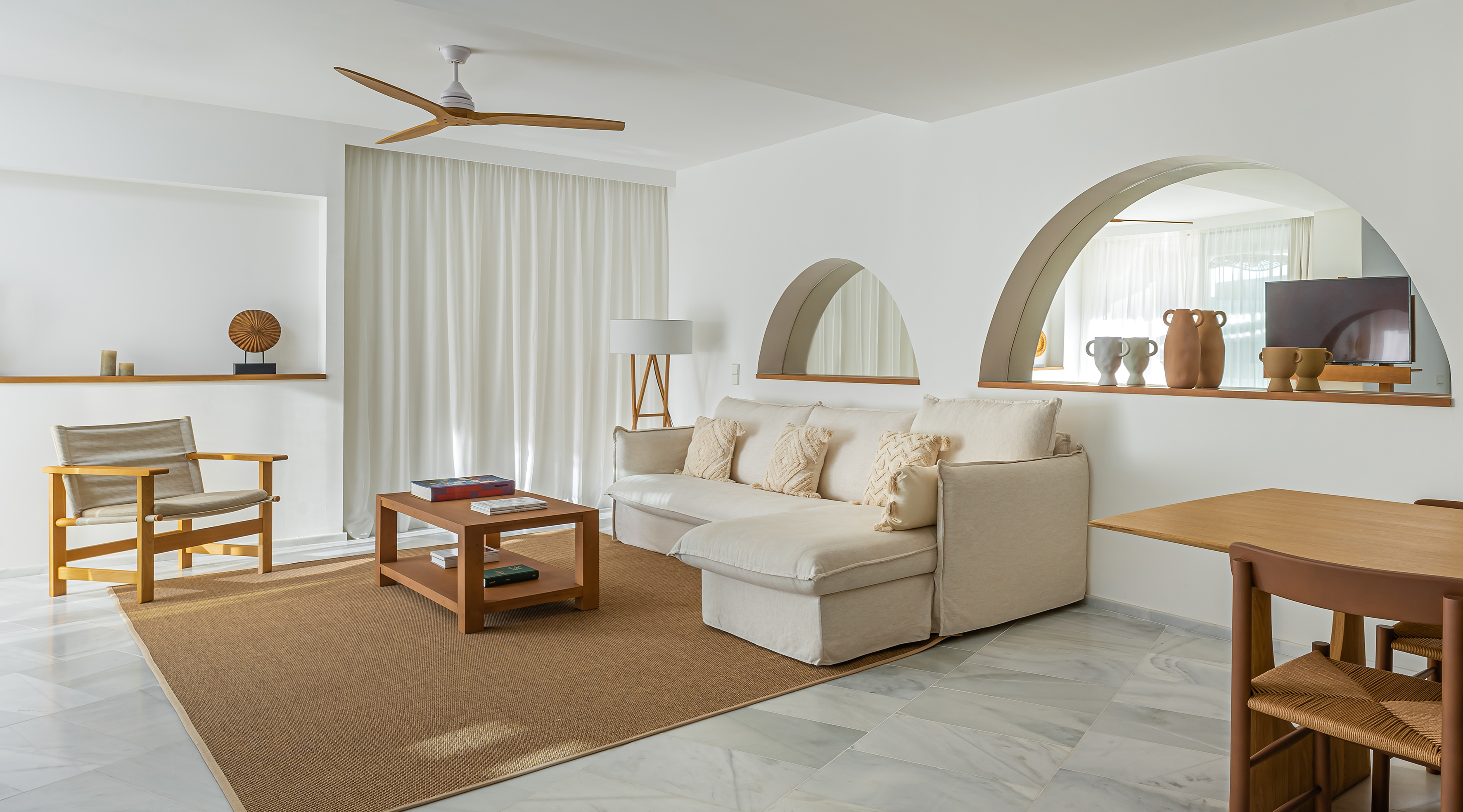 Modern neutral living room with beige sectional sofa, wood furniture, arched details.