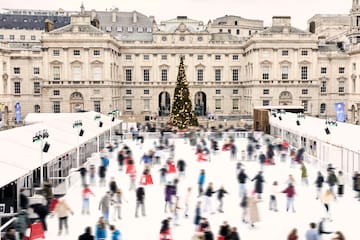 a large crowd of people ice skating in front of a large building