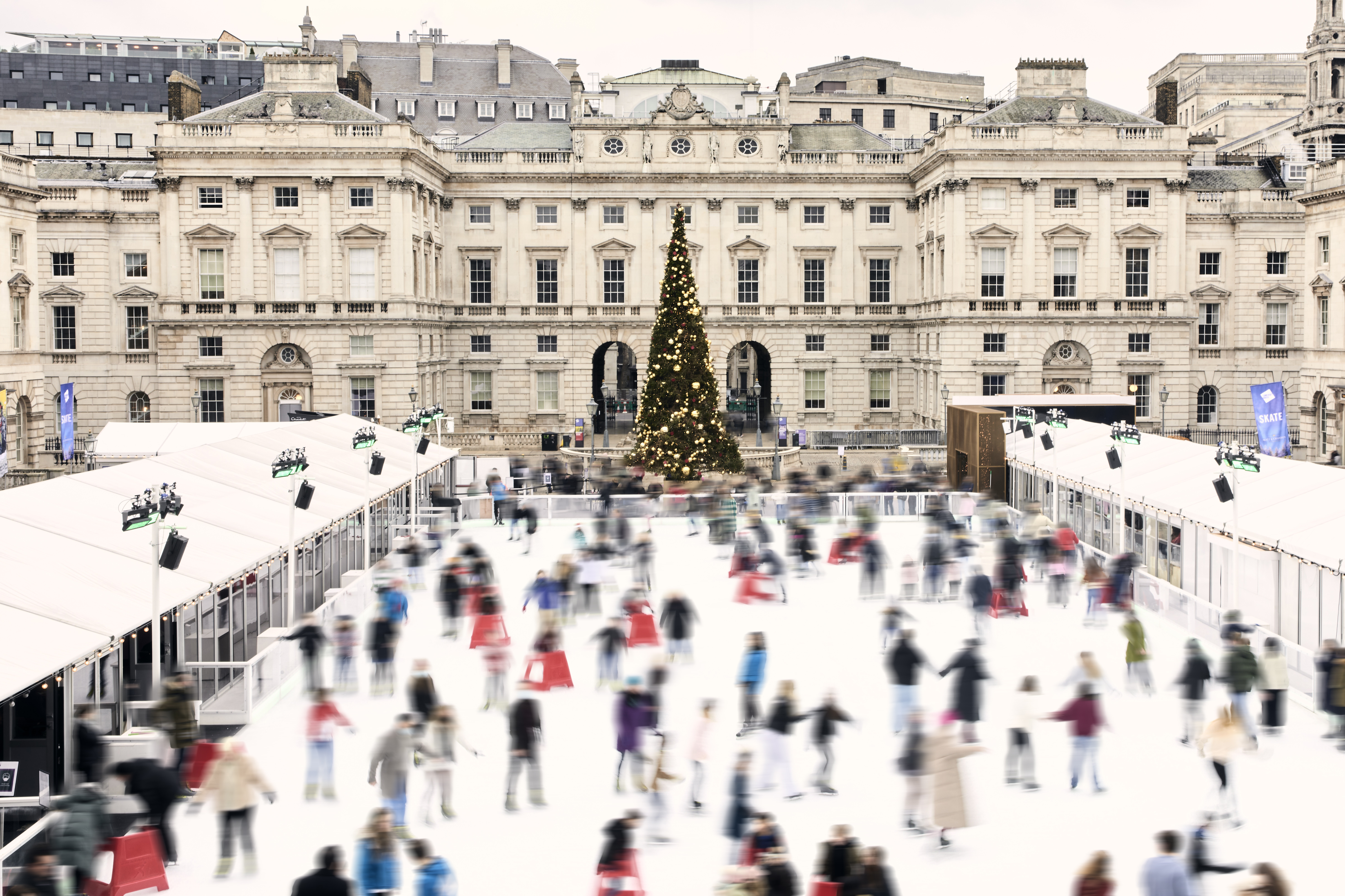 a large crowd of people ice skating in front of a large building