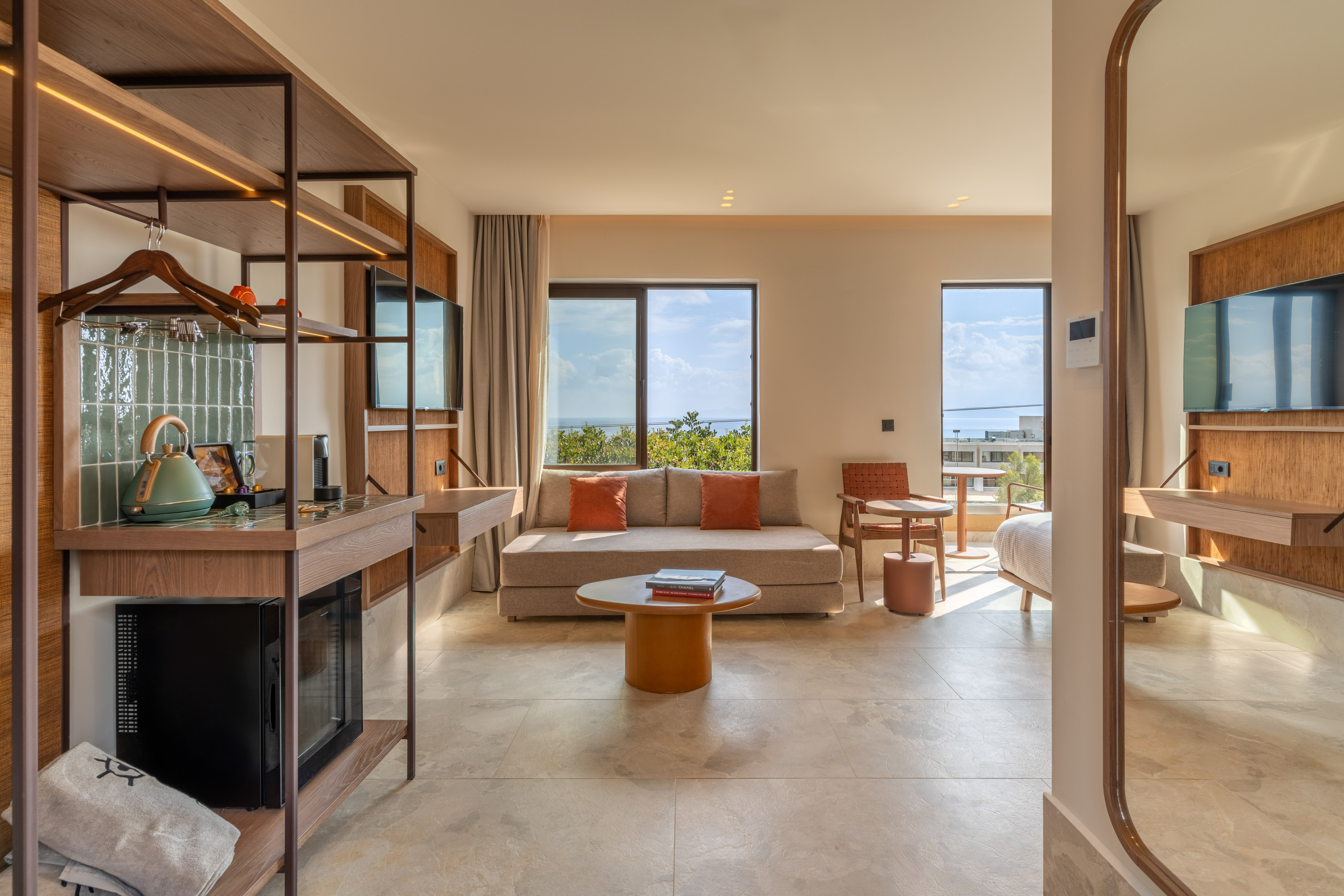 Modern hotel suite with sea view, kitchenette, and bright living area.