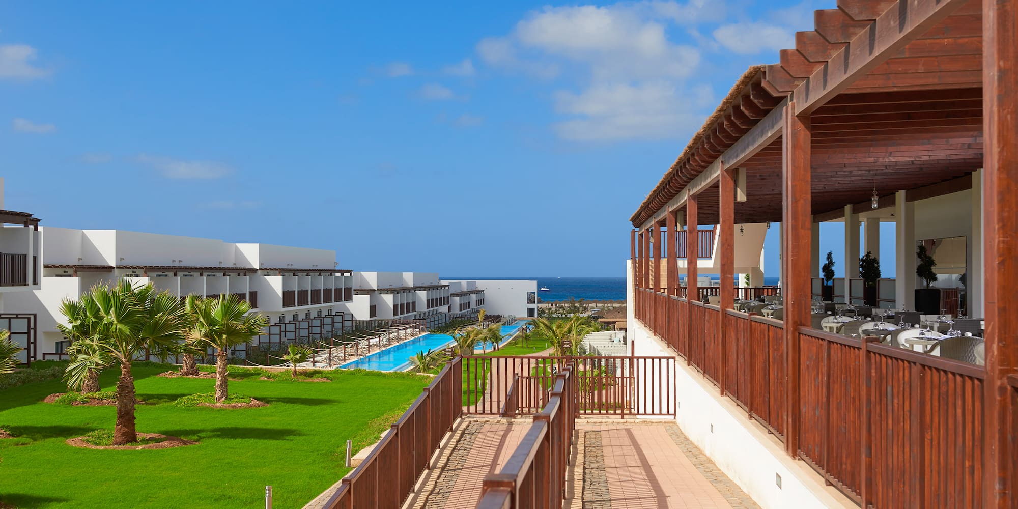 a deck with a pool and grass in front of it