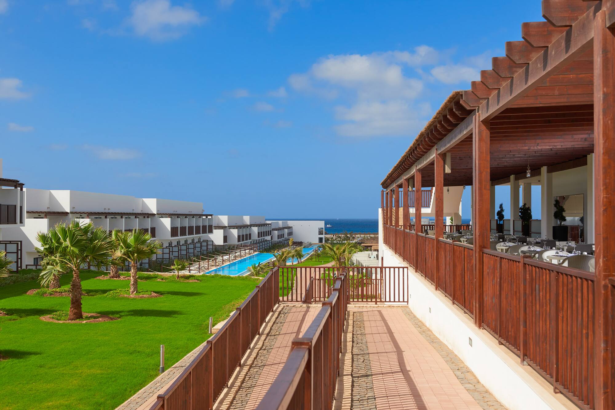 a deck with a pool and grass in front of it