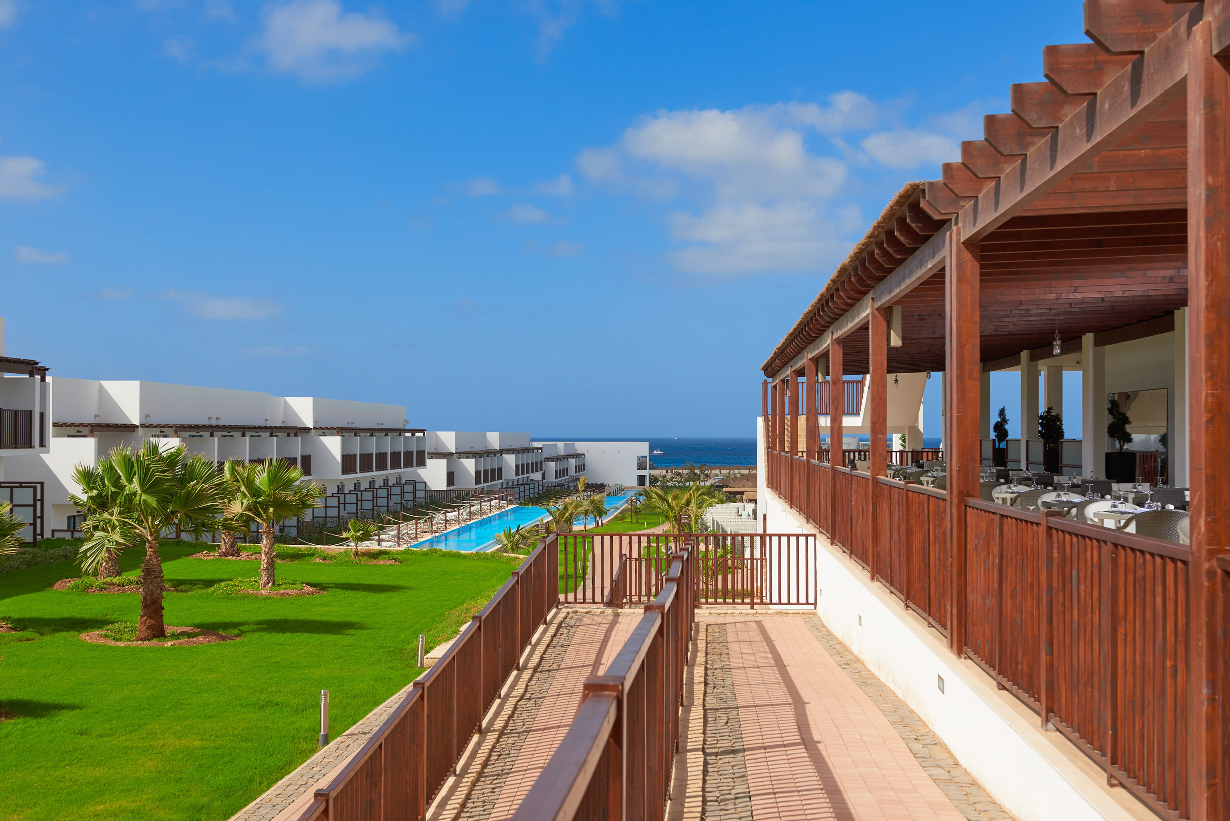 a deck with a pool and grass in front of it