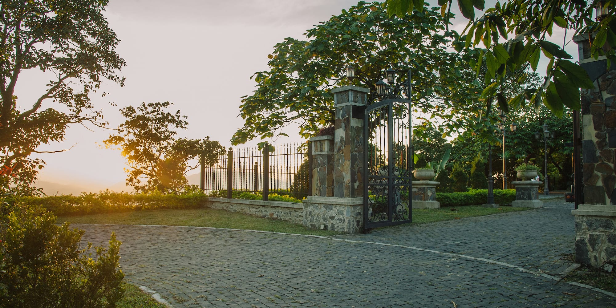a gated driveway with trees and a fence