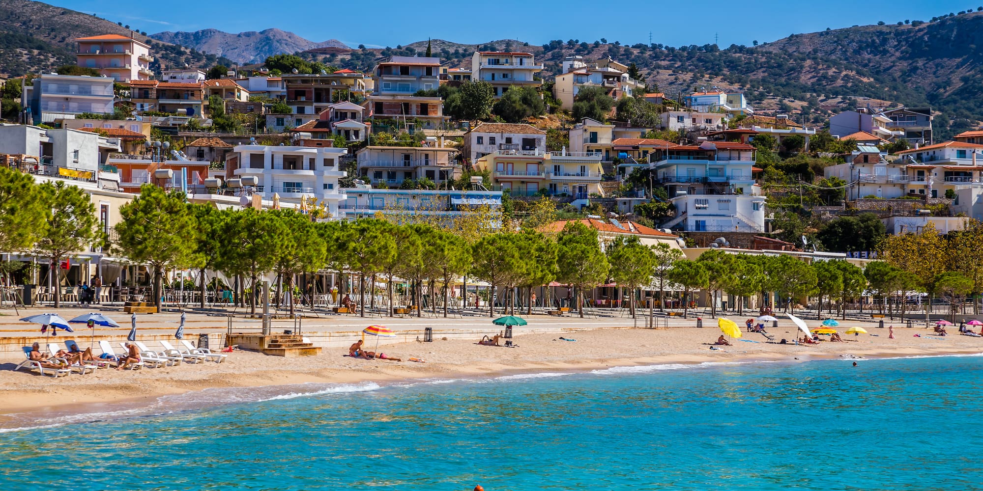 a beach with trees and buildings in the background