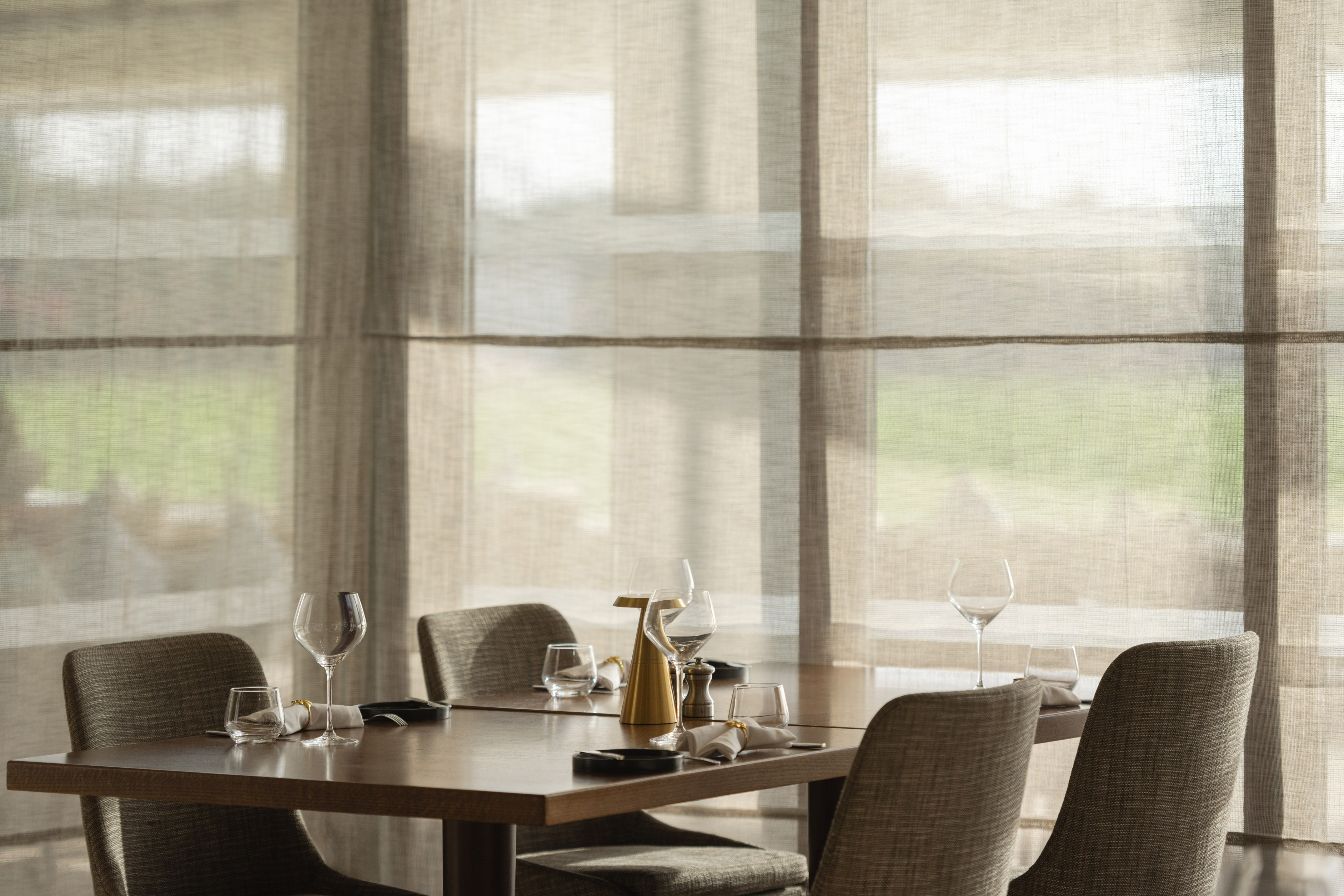Elegant restaurant dining table set, sheer window blinds, natural light.