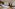 Luxury hotel bedroom with king bed, white linens, wood furniture, terracotta floor.