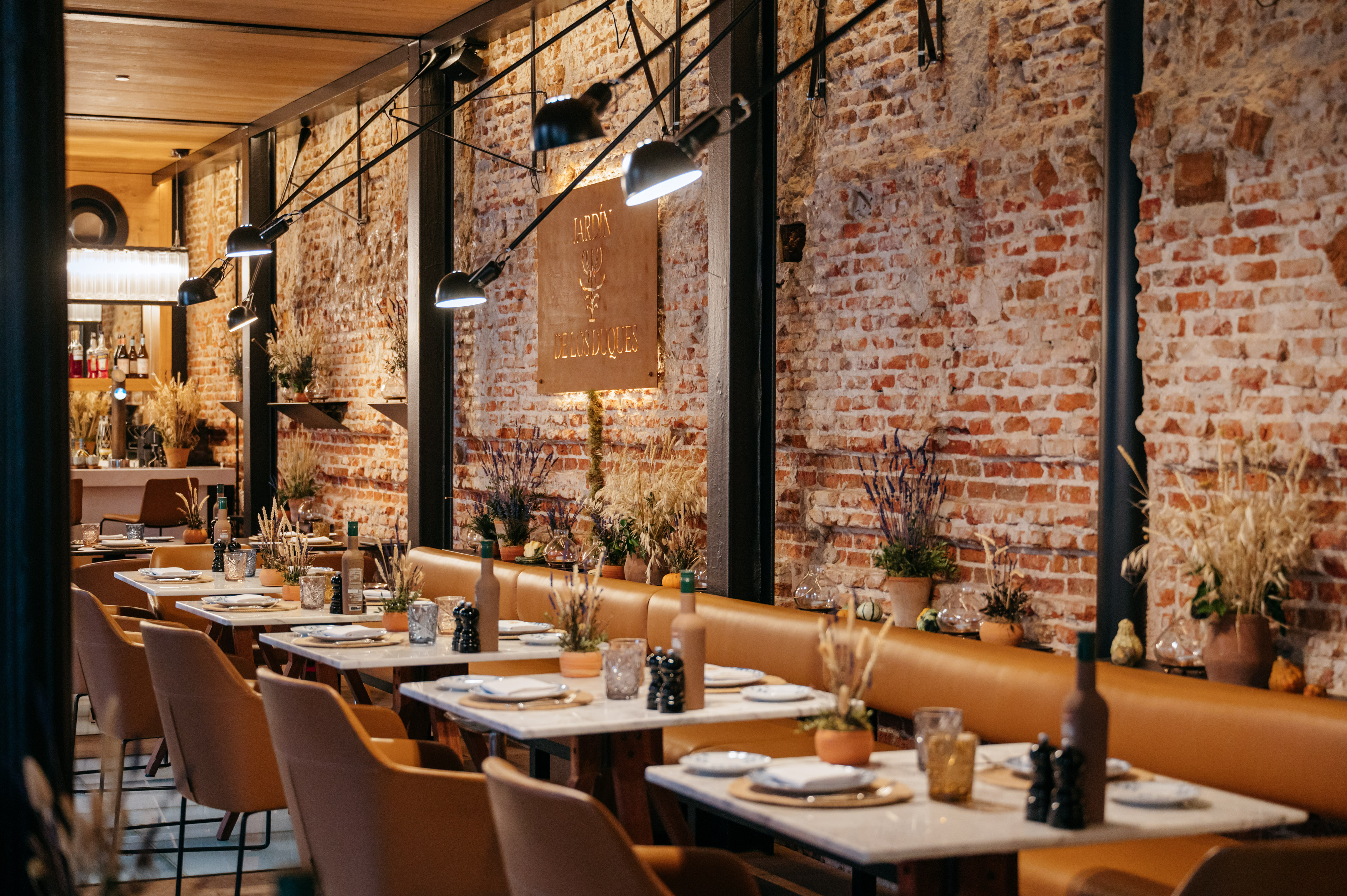 Restaurant interior with exposed brick, leather banquettes, and industrial lighting.