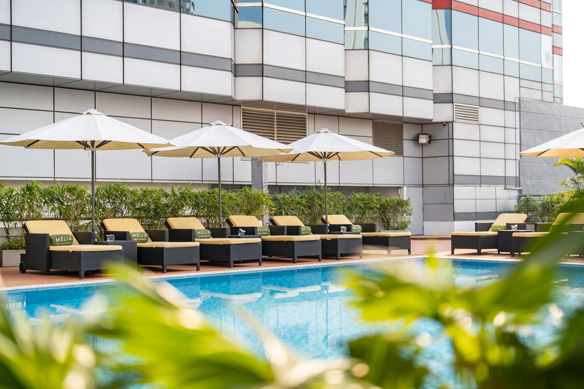 Meliá hotel swimming pool with white umbrellas and lounge chairs.