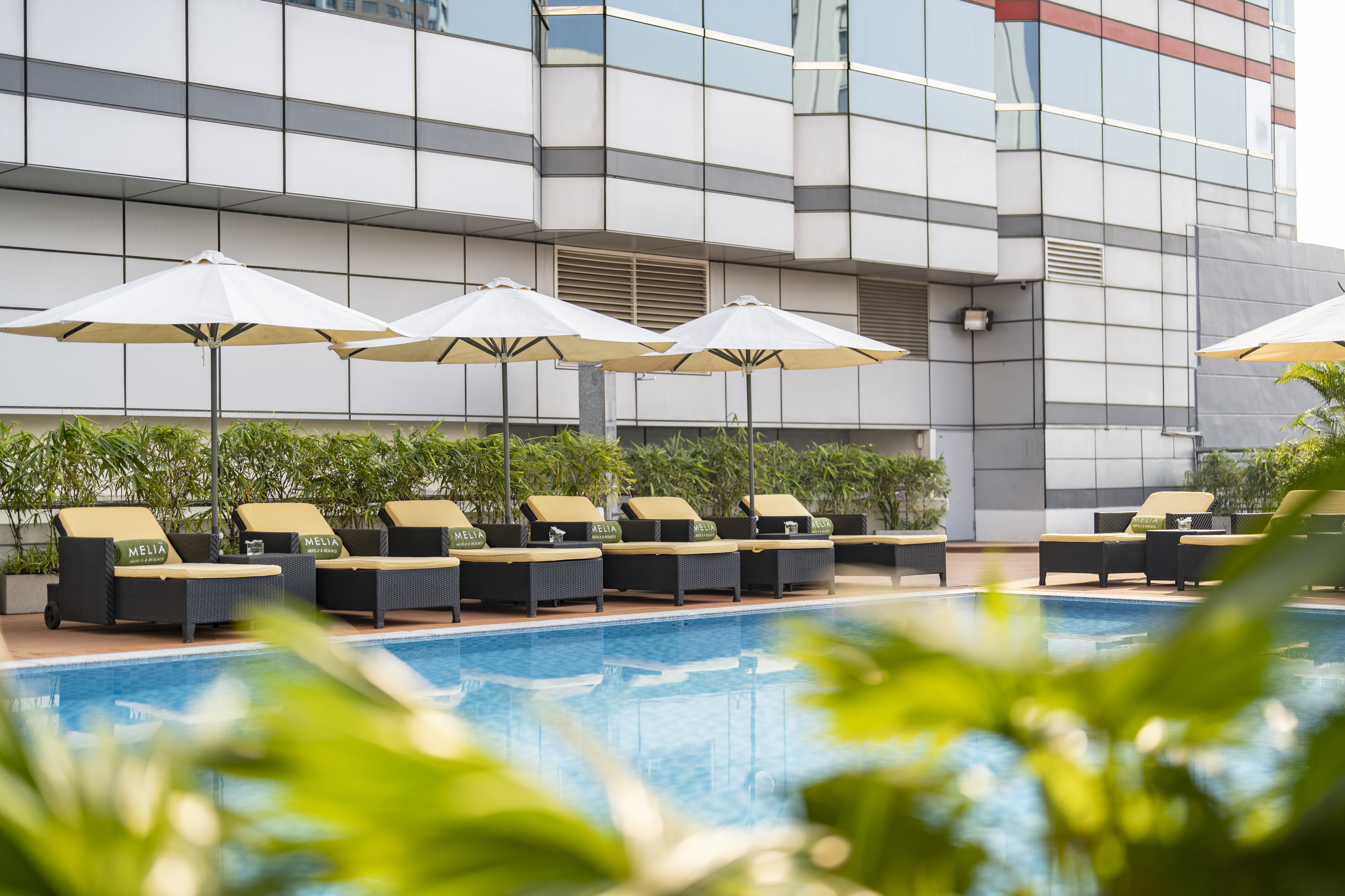 Meliá hotel swimming pool with white umbrellas and lounge chairs.