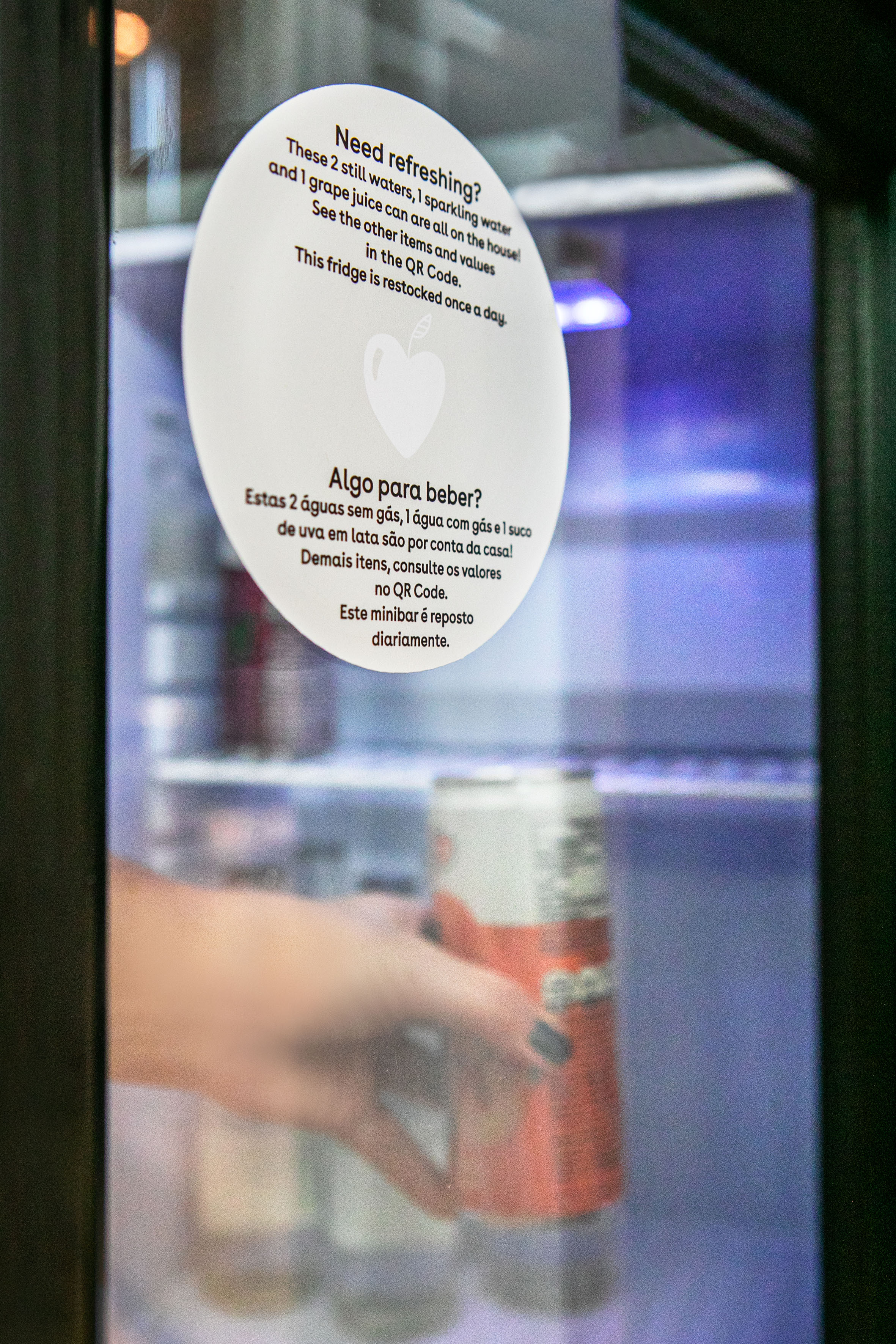 Minibar fridge with complimentary waters, grape juice, and hand taking a can.