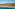 Beachfront hotel with orange buildings, palm trees, sandy beach, and blue sea.