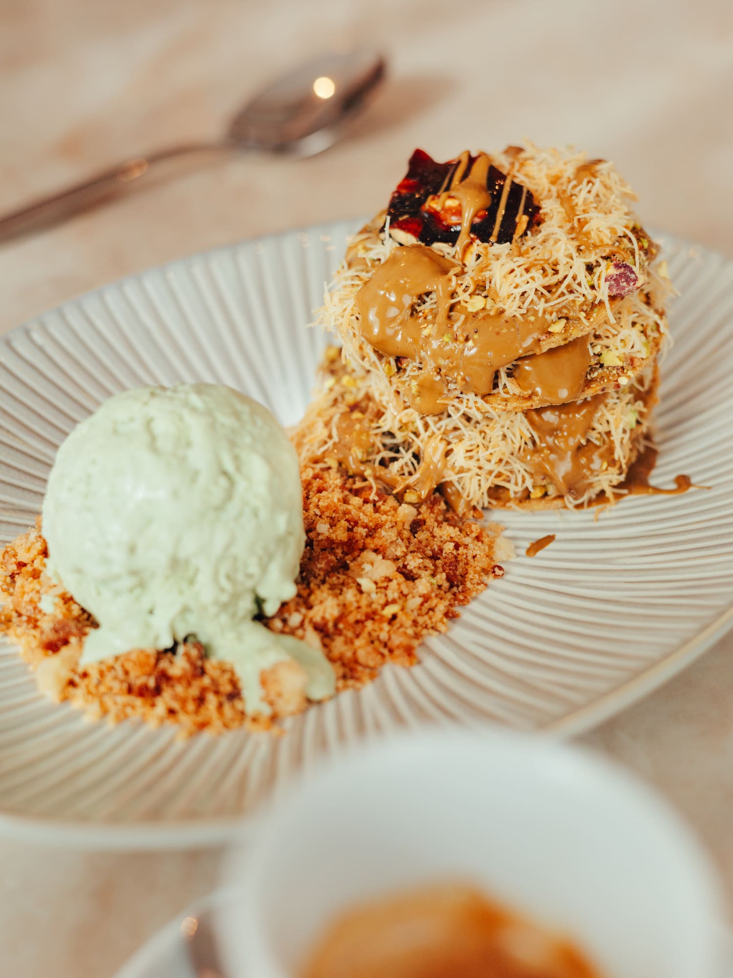Stacked kunafa dessert with caramel, pistachios, and green ice cream.
