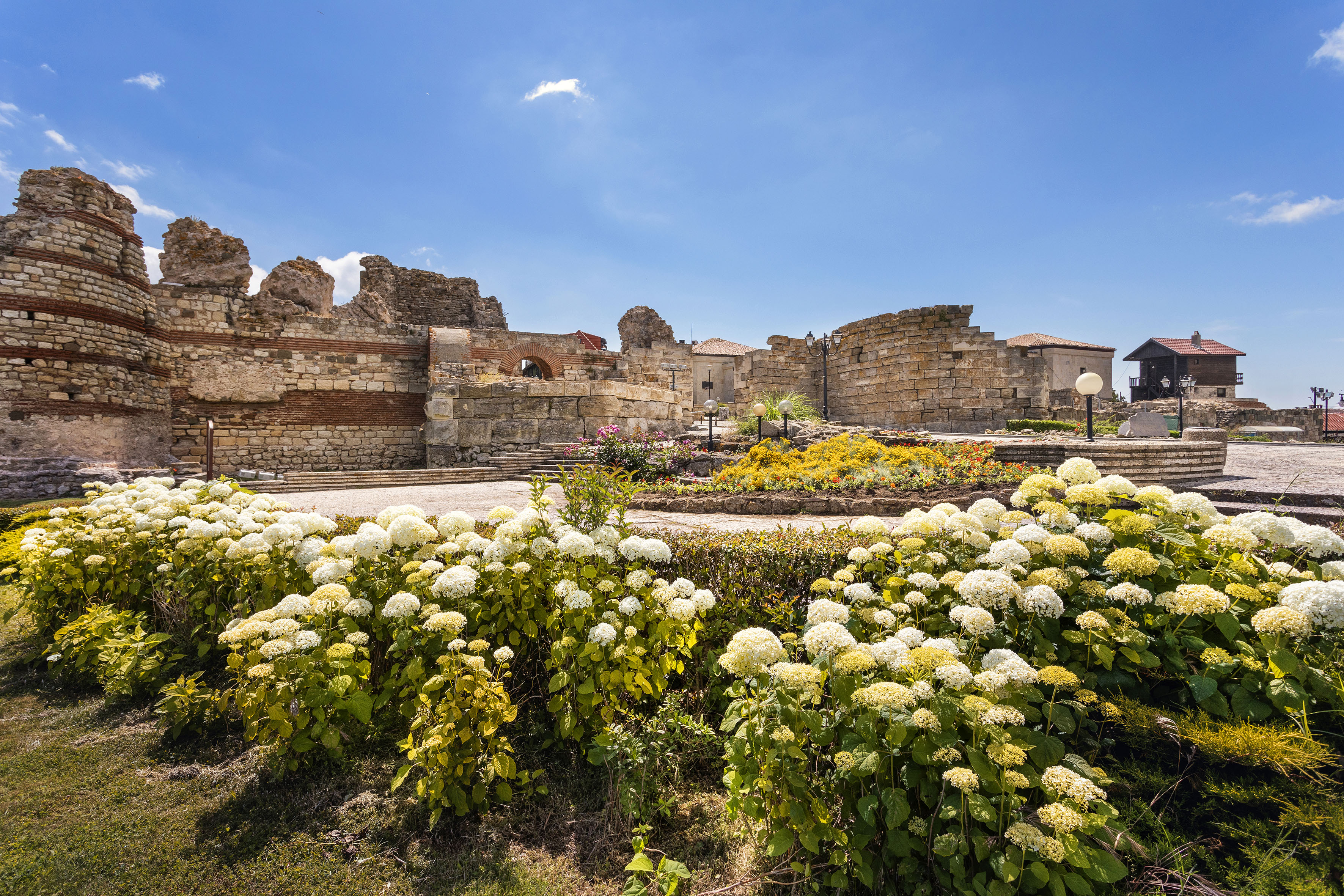 a garden with flowers in front of a stone building