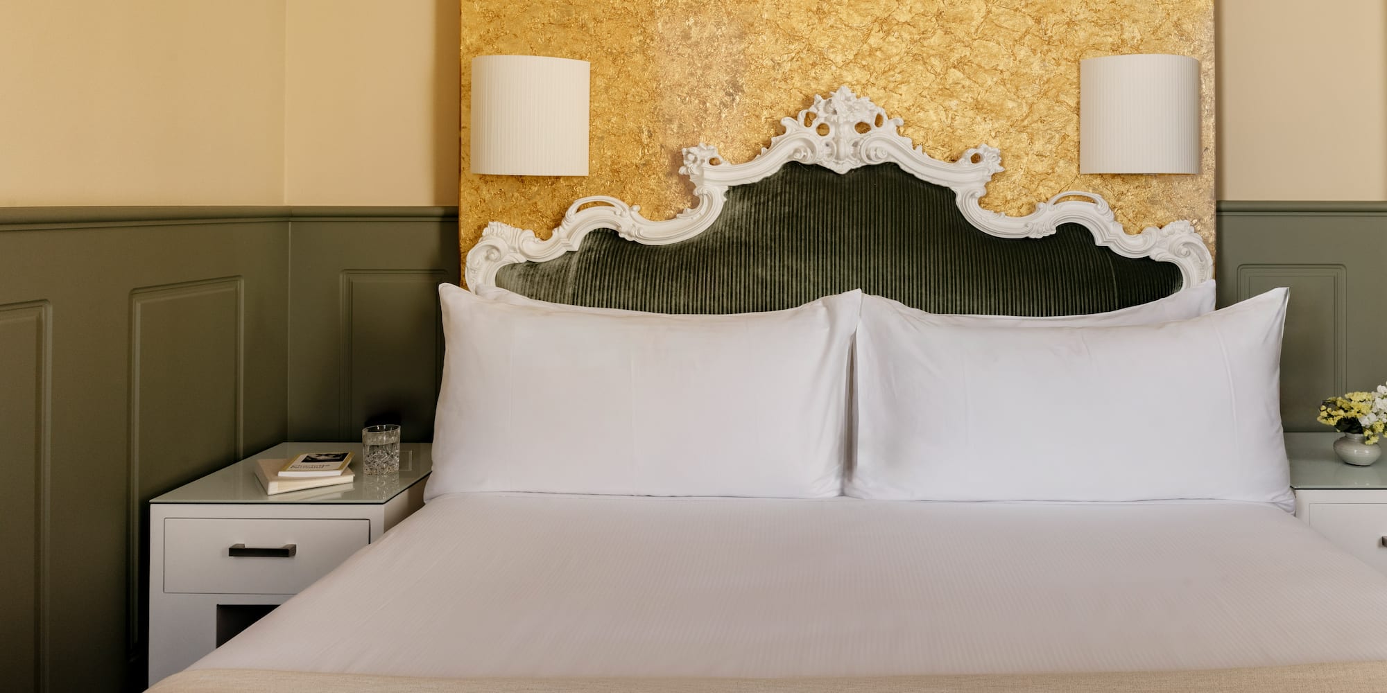 Dormitorio elegante con cabecero verde terciopelo y pared dorada.