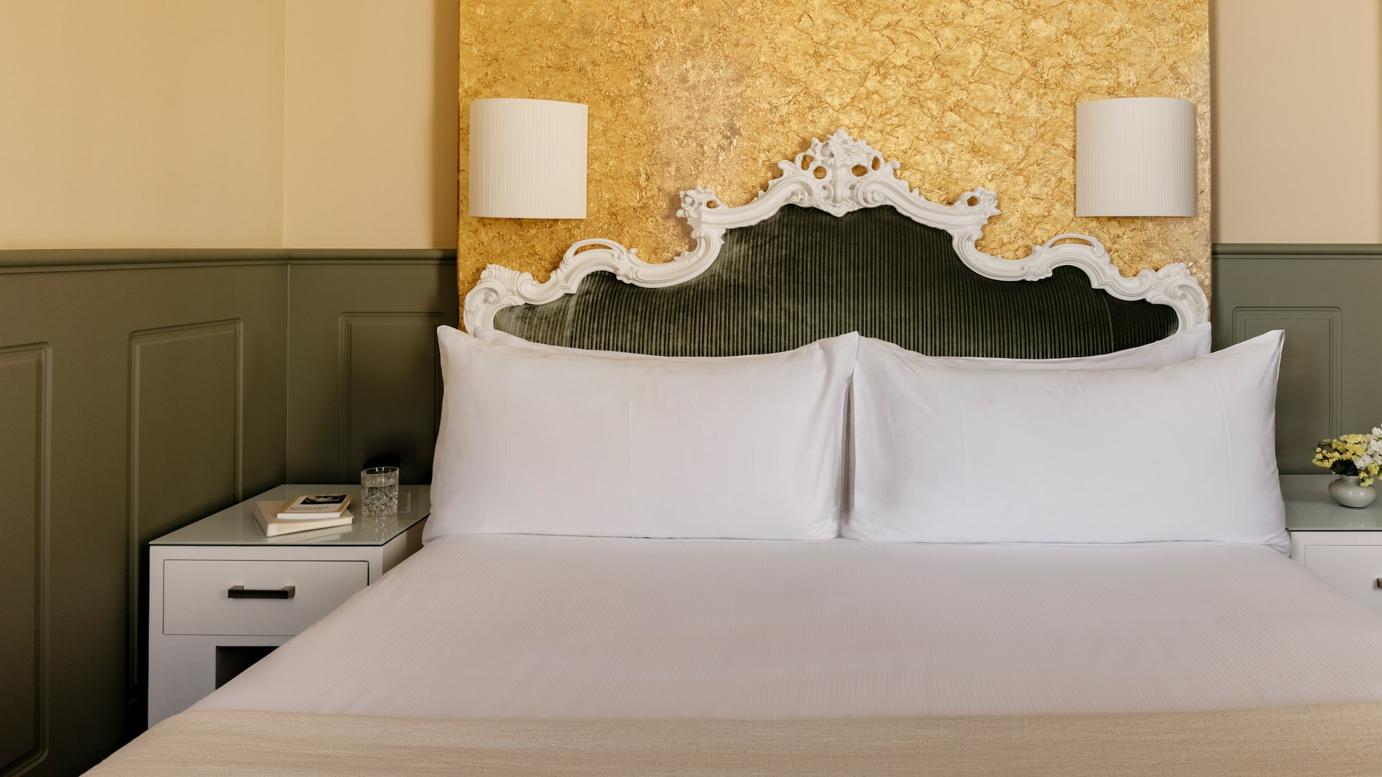 Dormitorio elegante con cabecero verde terciopelo y pared dorada.