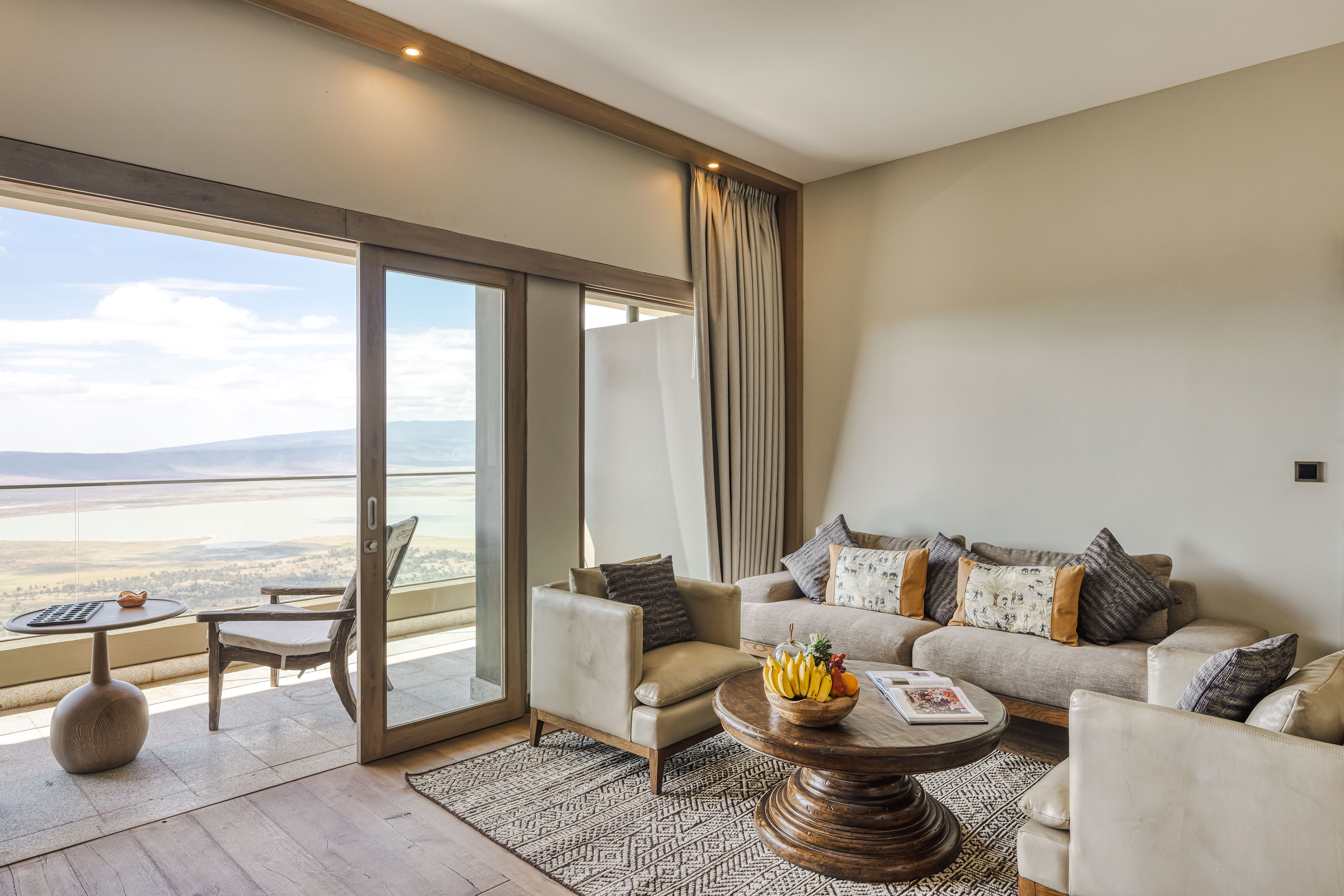 Safari lodge suite living room with balcony overlooking crater lake.