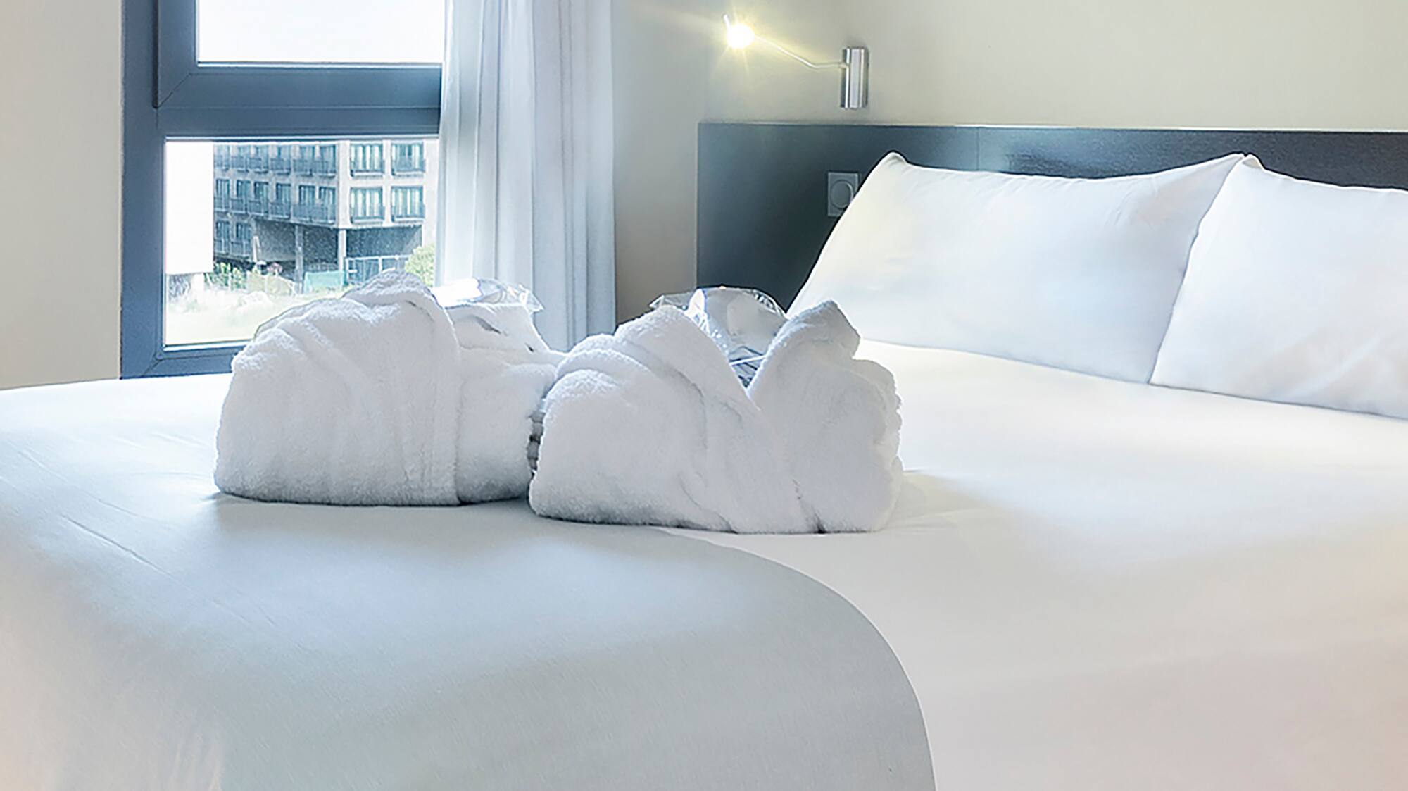 a bed with white sheets and towels
