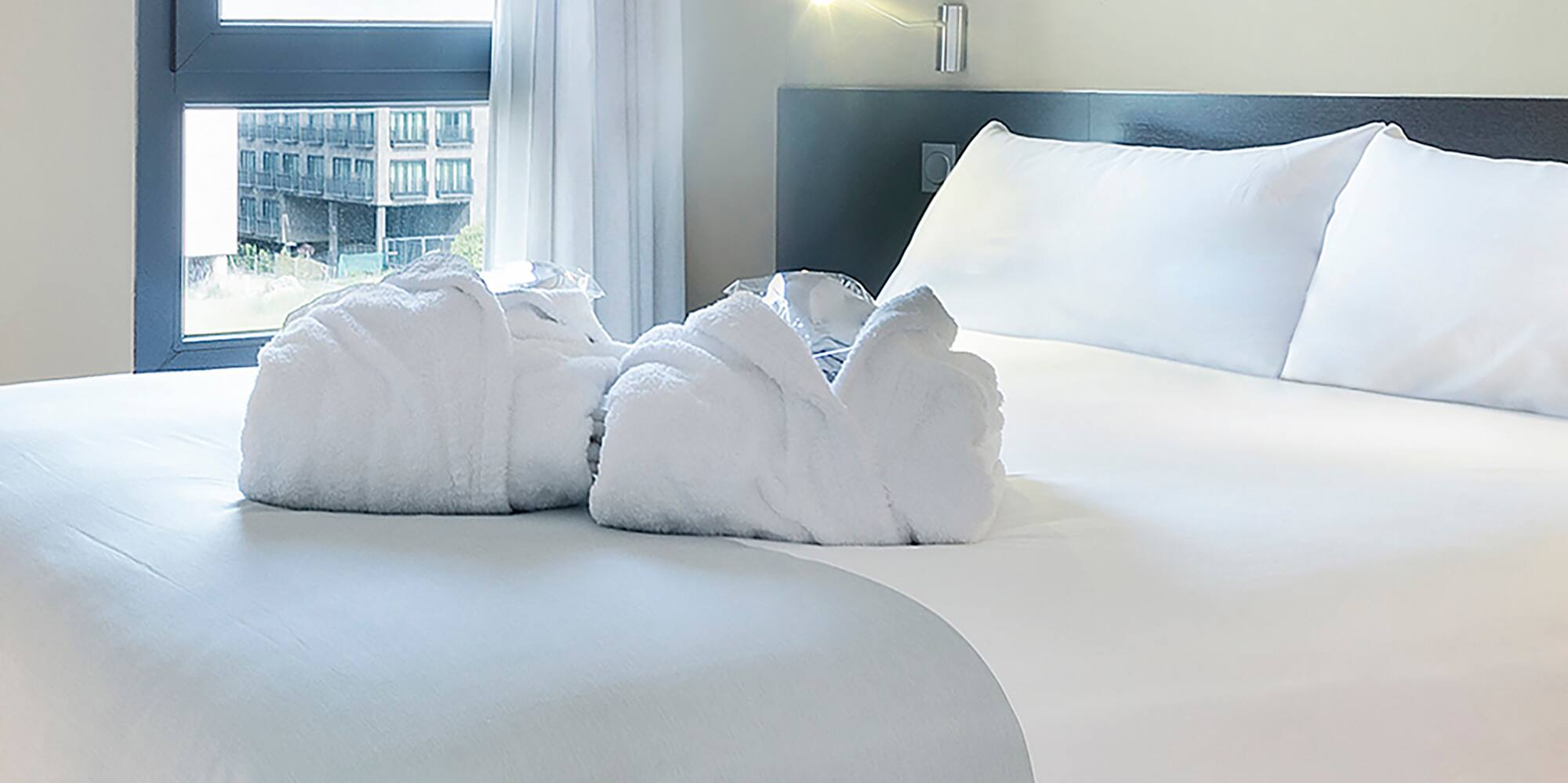 a bed with white sheets and towels