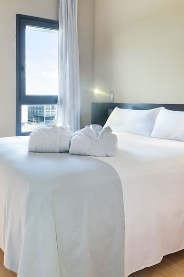 a bed with white sheets and towels