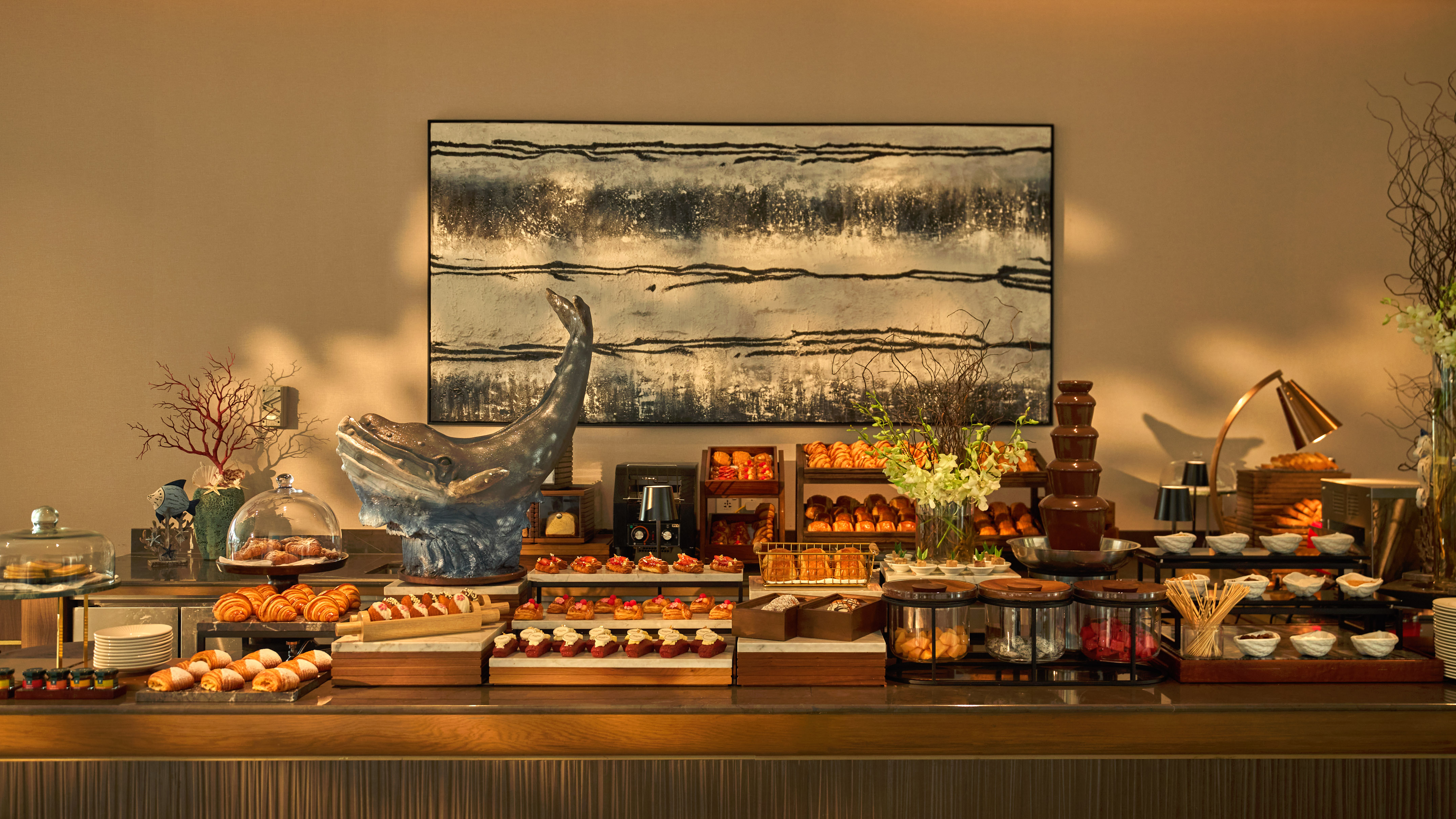 Elegant hotel buffet: pastries, croissants, chocolate fountain, desserts.