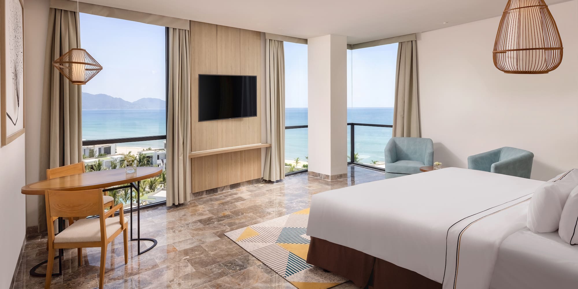 a room with a bed and a table and chairs by the ocean