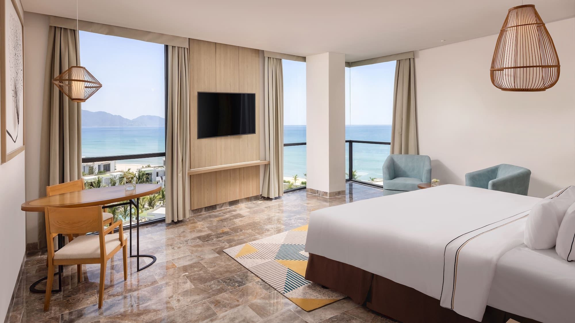 a room with a bed and a table and chairs by the ocean