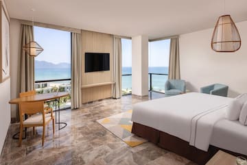 a room with a bed and a table and chairs by the ocean
