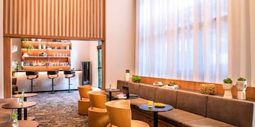 a room with a long couch and tables and chairs