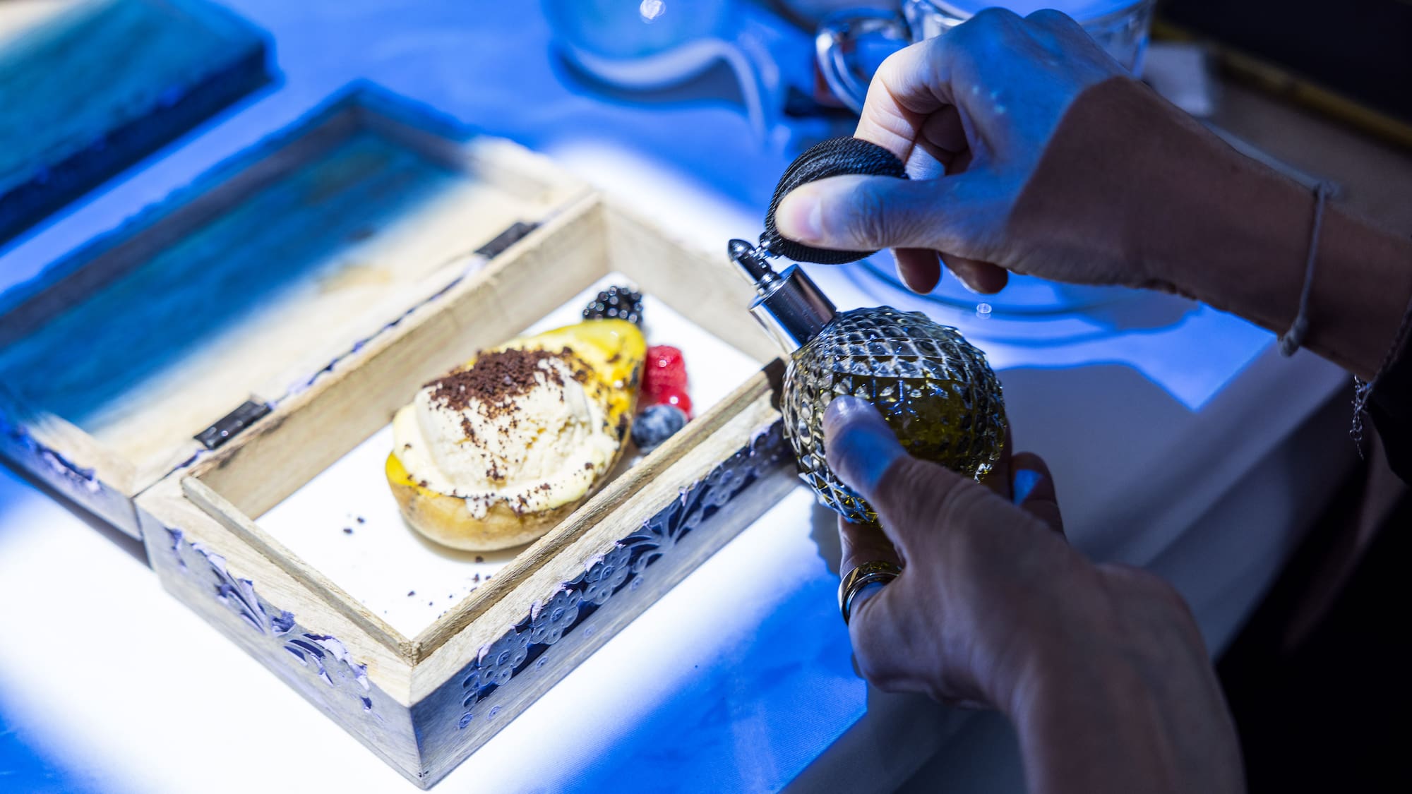a person spraying perfume on a tray