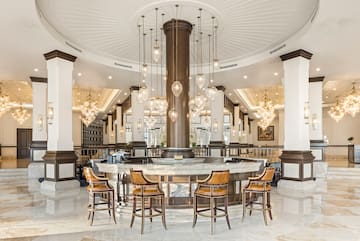 a large round table with chairs and chandeliers in a room