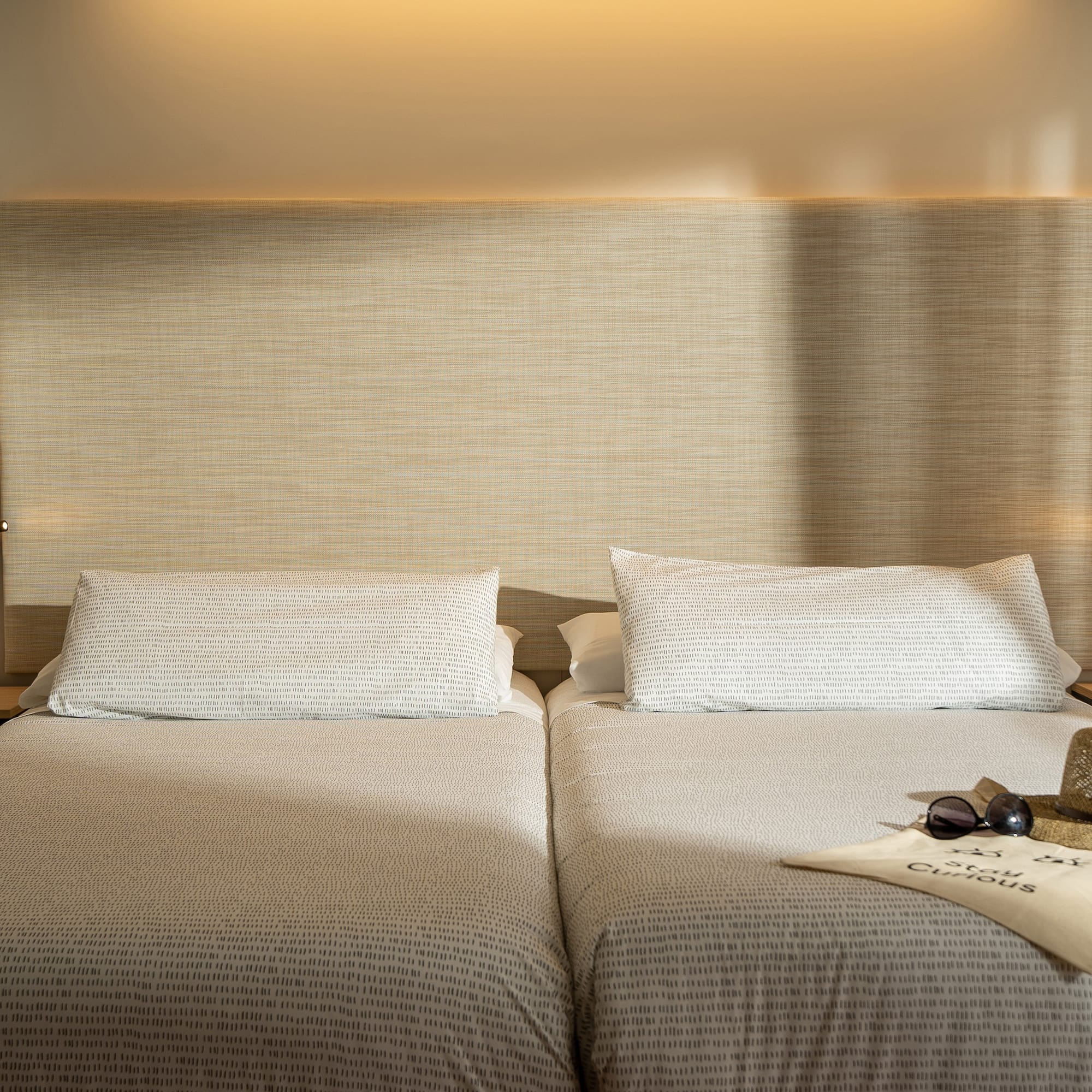 a pair of beds with a pair of sunglasses and a hat on top of it