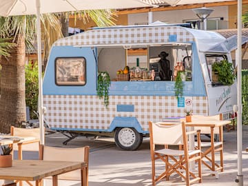 a food truck with tables and chairs under umbrellas