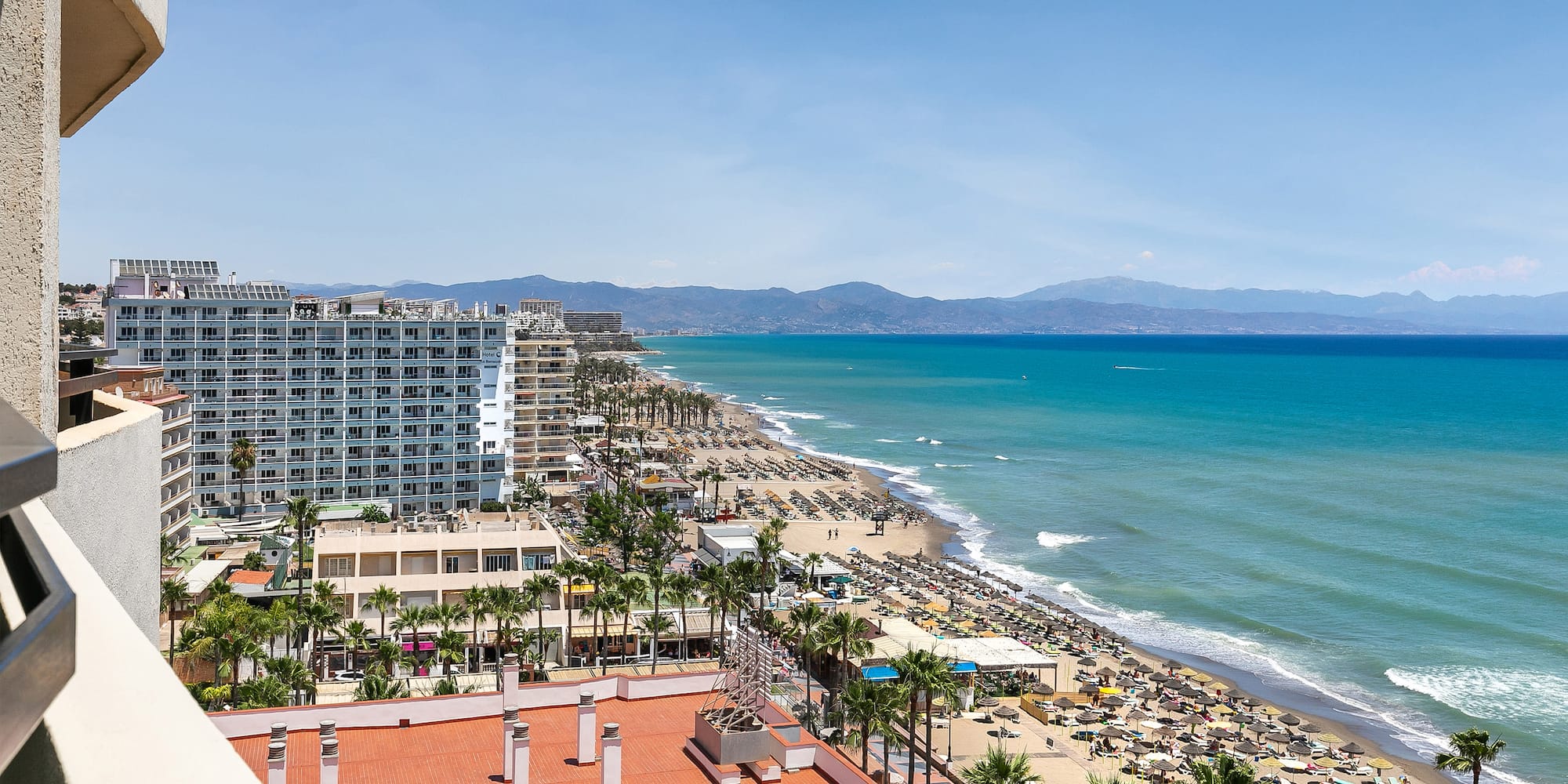 a beach with buildings and palm trees