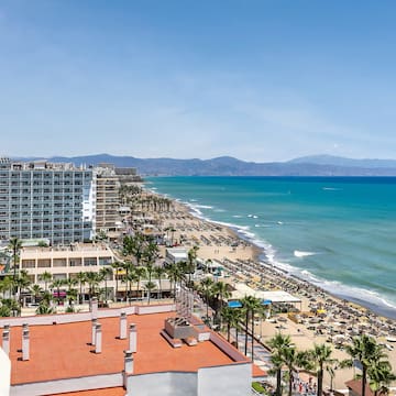 a beach with buildings and palm trees