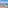 Sunny beach resort with hotels, palm trees, turquoise sea, and mountains.