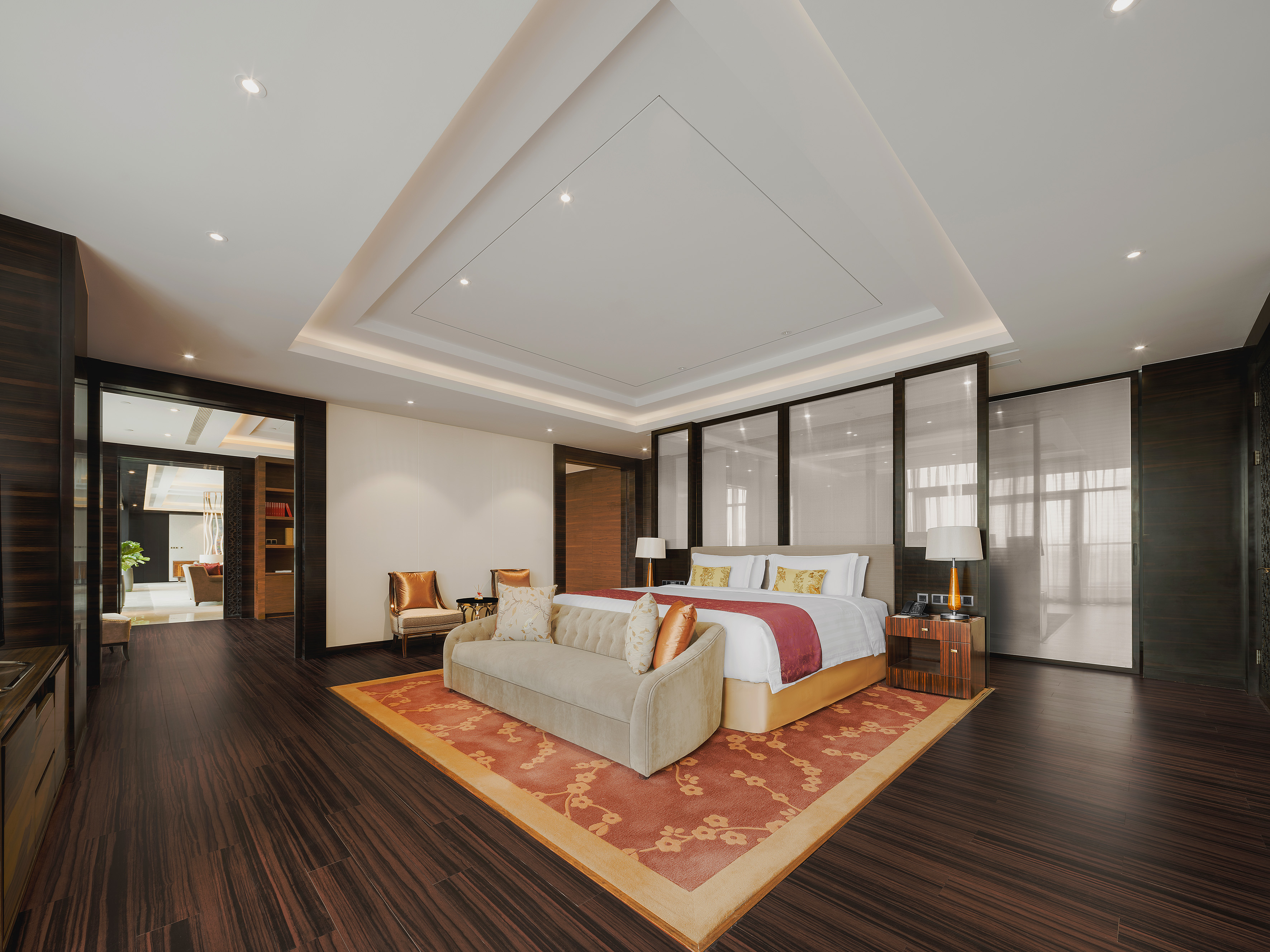 Luxury hotel suite bedroom with king bed, sofa, and elegant decor.