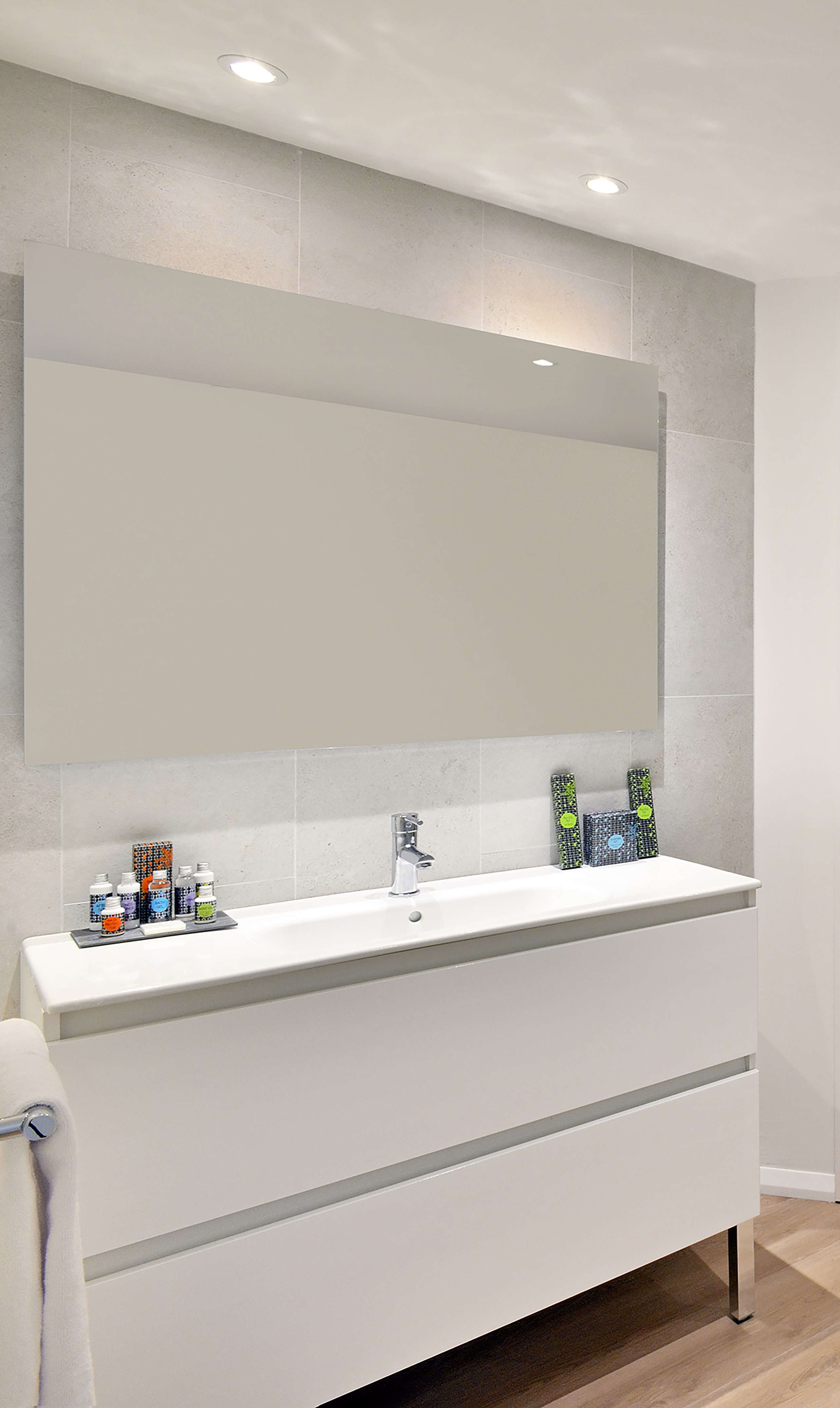 Modern white bathroom vanity, integrated sink, large mirror, gray tiled wall.