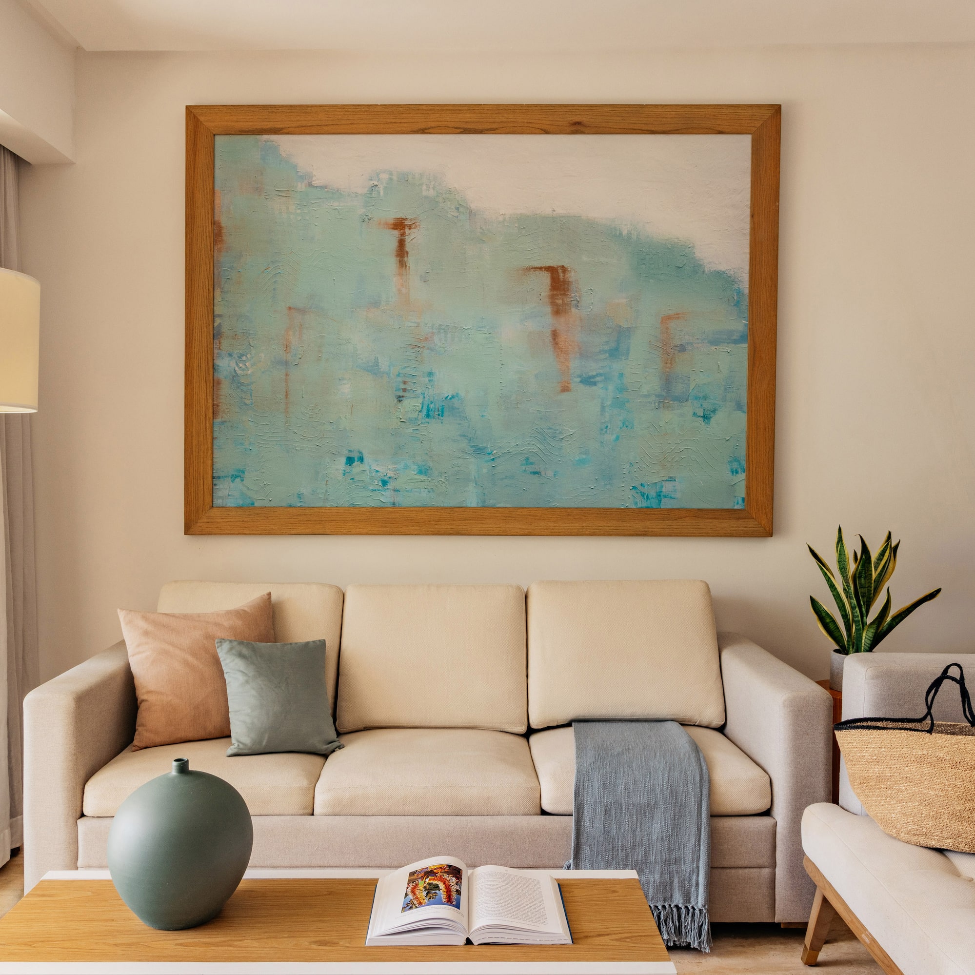 Modern living room with beige sofa, abstract blue wall art, and coffee table.