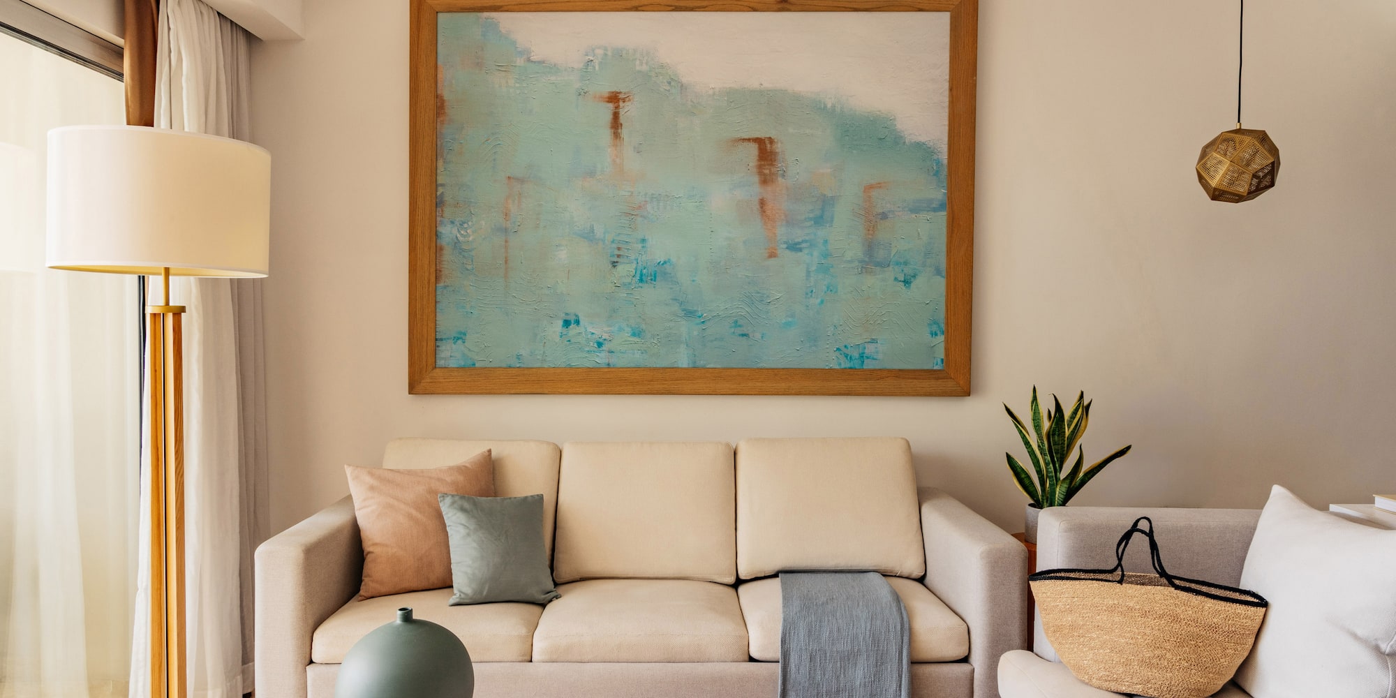 Modern living room with beige sofa, abstract blue wall art, and coffee table.