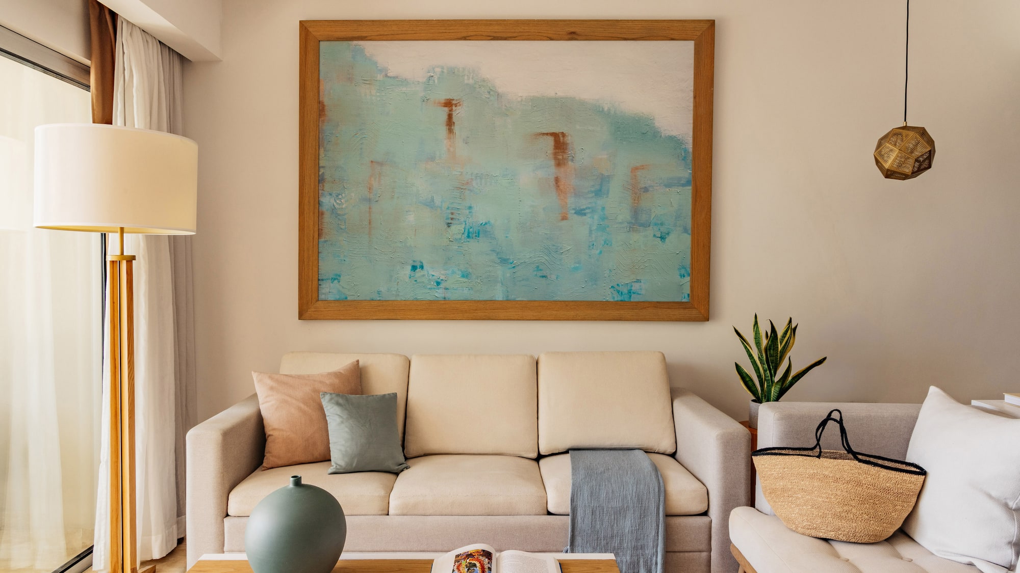 Modern living room with beige sofa, abstract blue wall art, and coffee table.