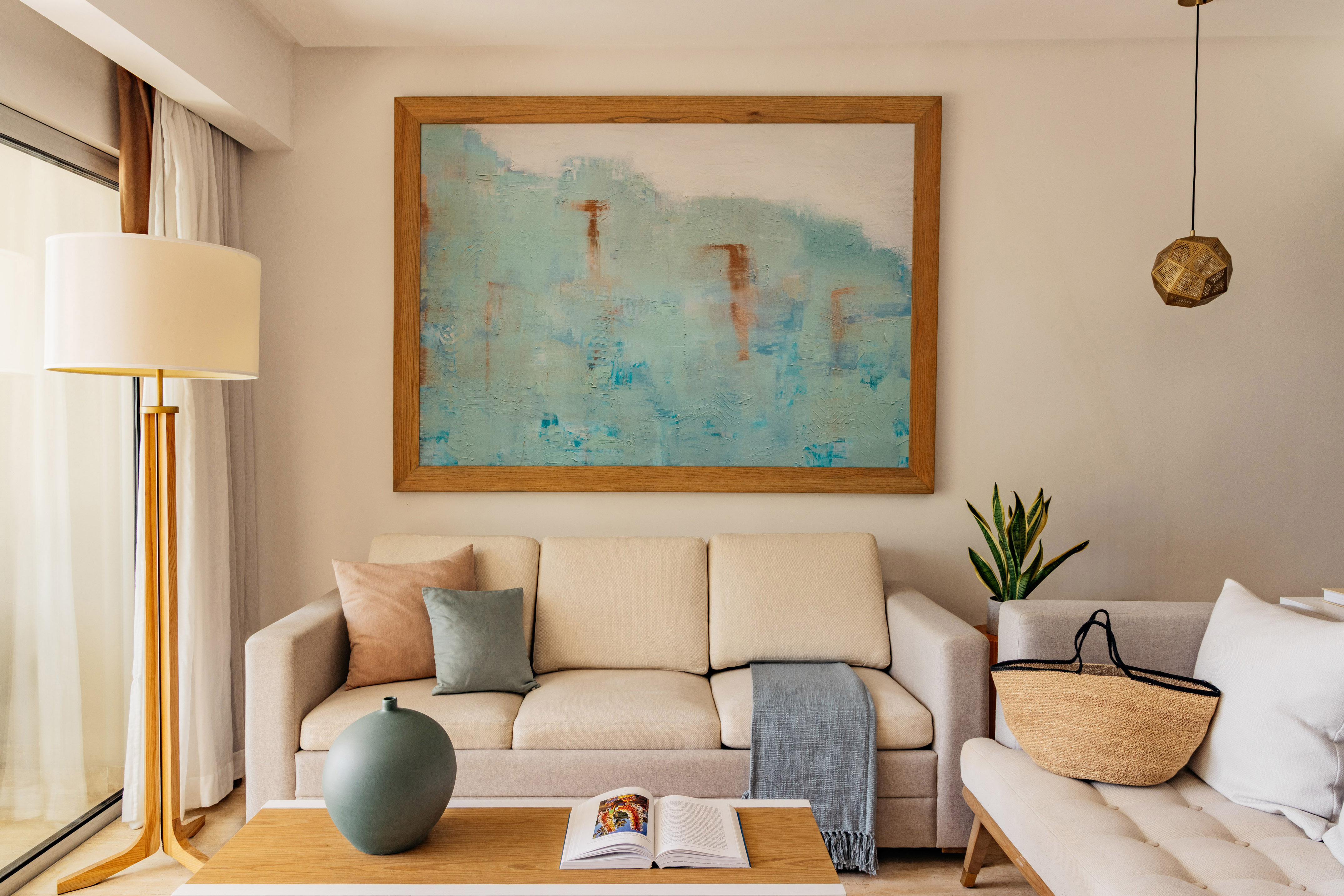 Modern living room with beige sofa, abstract blue wall art, and coffee table.