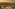 Woman in red dress on rooftop bar, city and mountains at sunset.