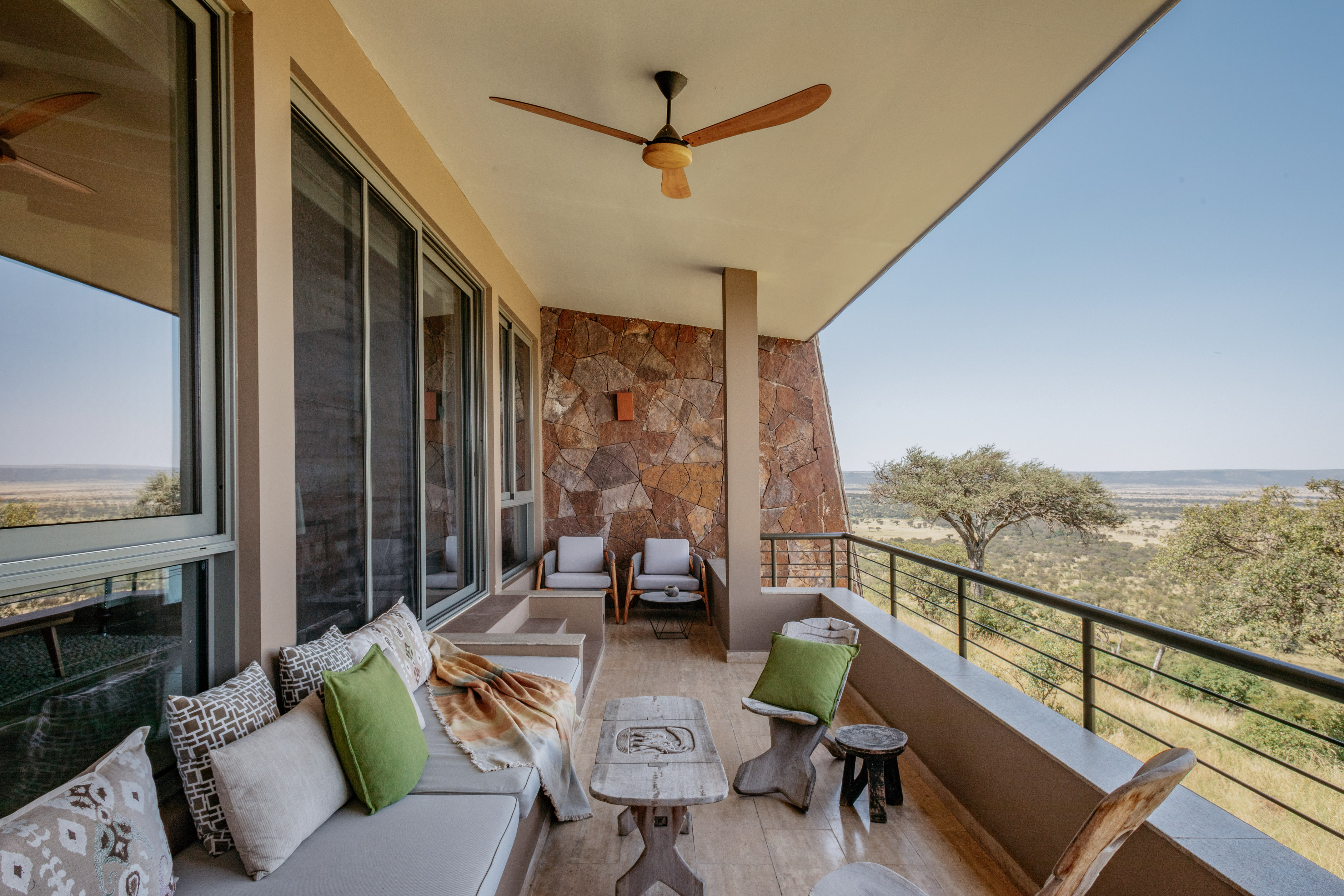 Safari lodge balcony with outdoor seating overlooking vast savannah.