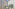 V-shaped modern building facade with trees and a street marked "TAXI".